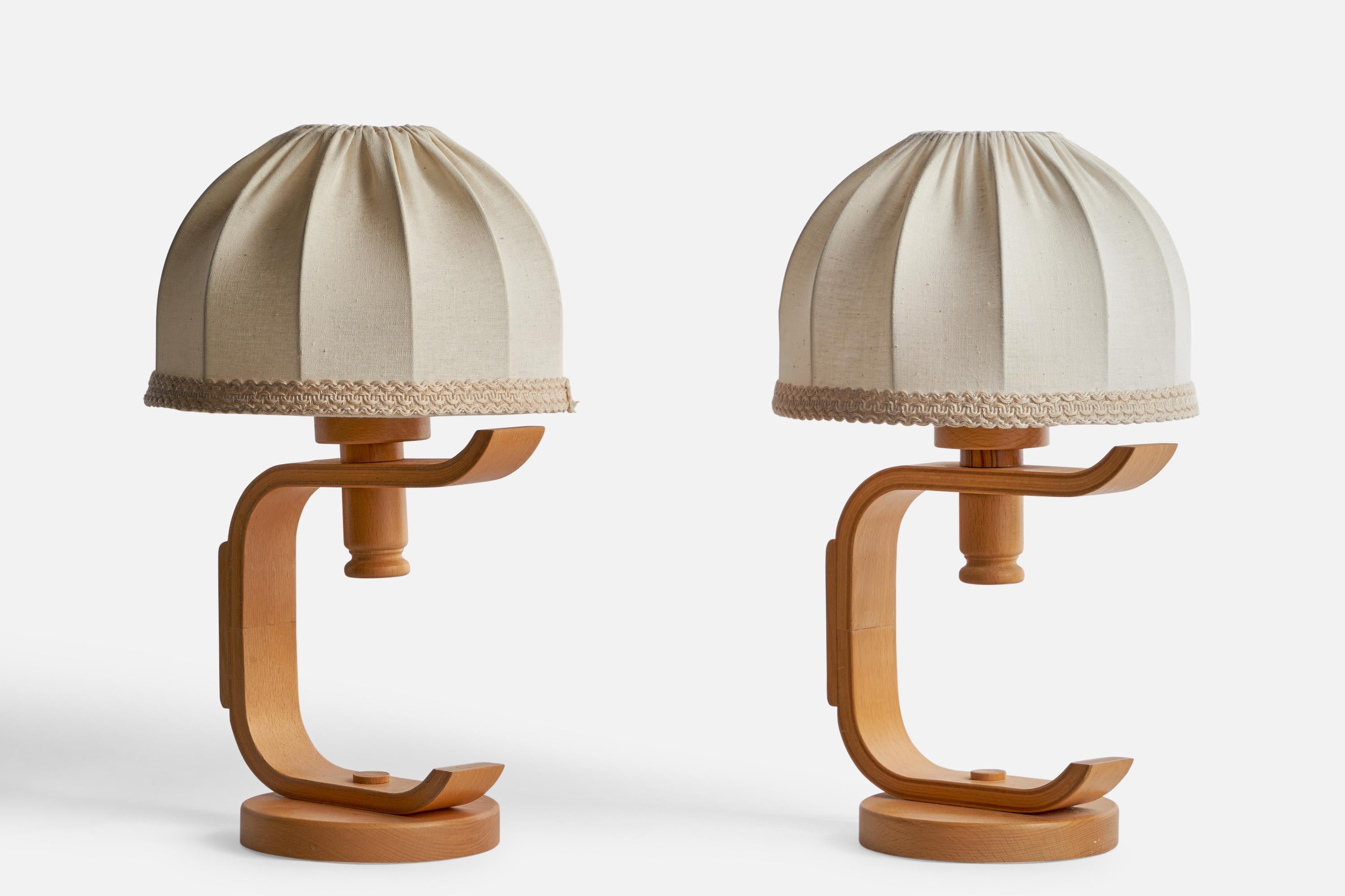 A pair of oak and off-white fabric table lamps designed and produced in Sweden, 1970s.

Overall Dimensions (inches): 15” H x 9” Diameter
Bulb Specifications: E-26 Bulbs
Number of Sockets: 2
All lighting will be converted for US usage. We is unable