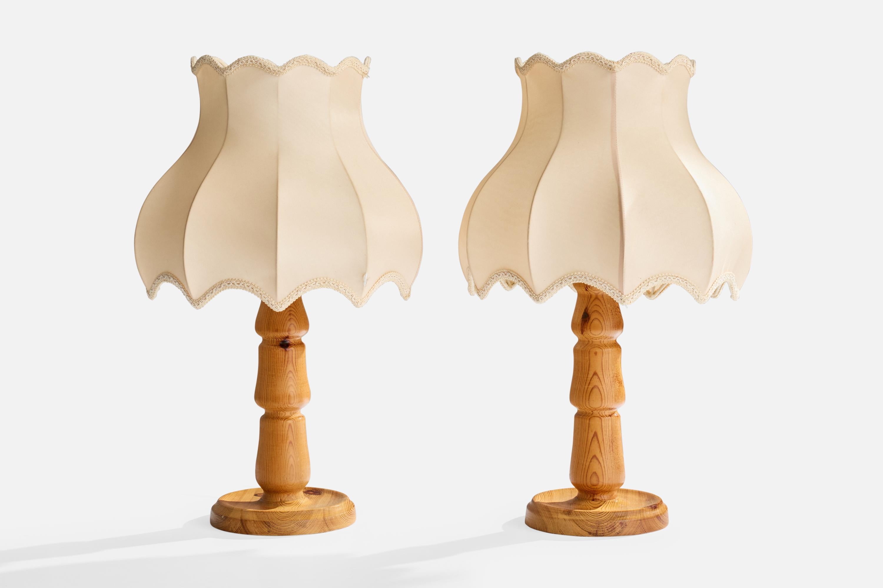 A pair of pine and beige fabric table lamps designed and produced in Sweden, c. 1970s.

Wear to wood consistent with age and use

Minor stains and wear to vintage lampshades consistent with age and use. Tear as illustrated.

Overall Dimensions