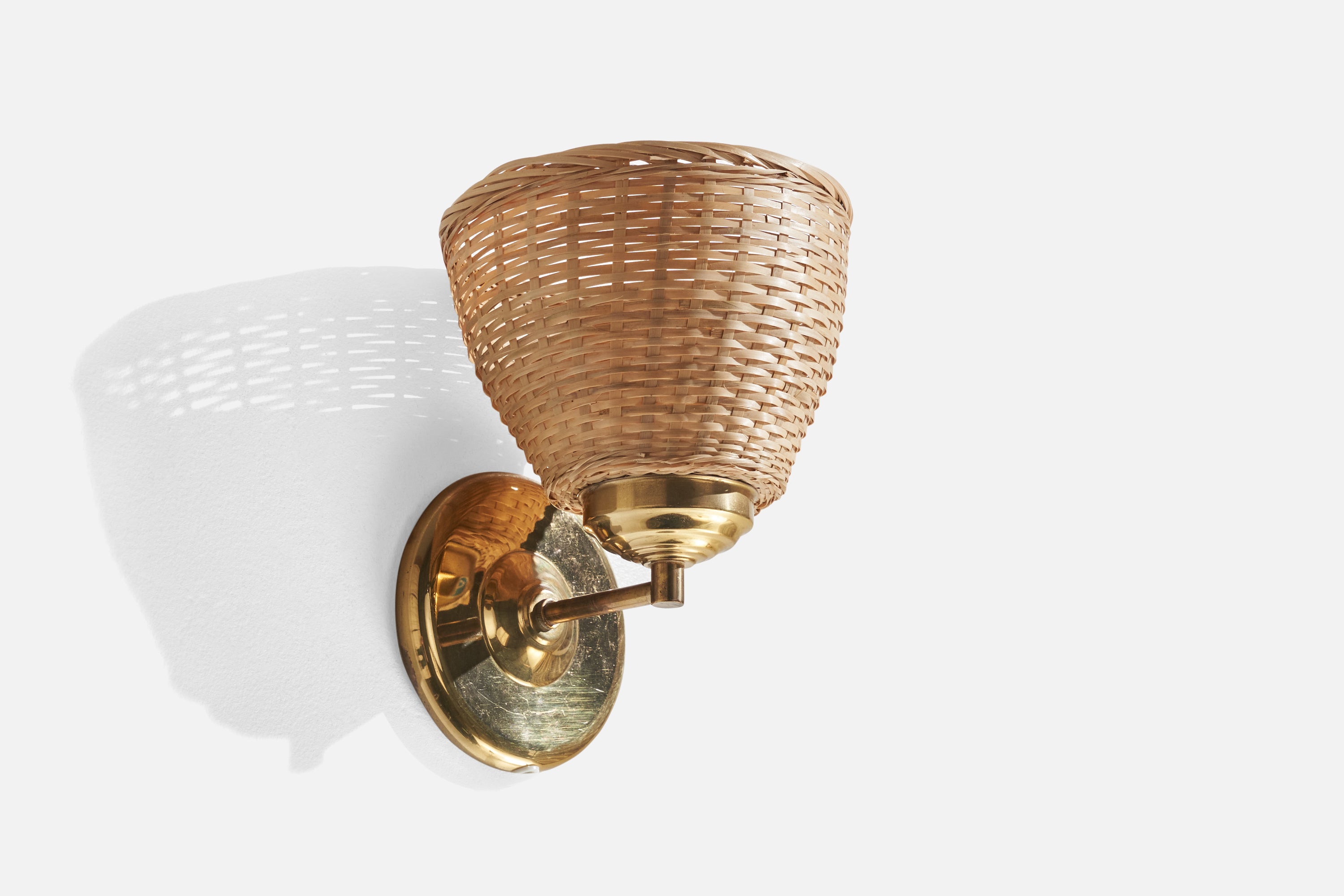 A brass and rattan wall light designed and produced in Sweden, c. 1970s.

Overall Dimensions (inches): 8.75” H x 7.15”  W x 7”  D
Back Plate Dimensions (inches): 5.05” H x 0.8” D
Bulb Specifications: E-26 Bulb
Number of Sockets: 1
All lighting will