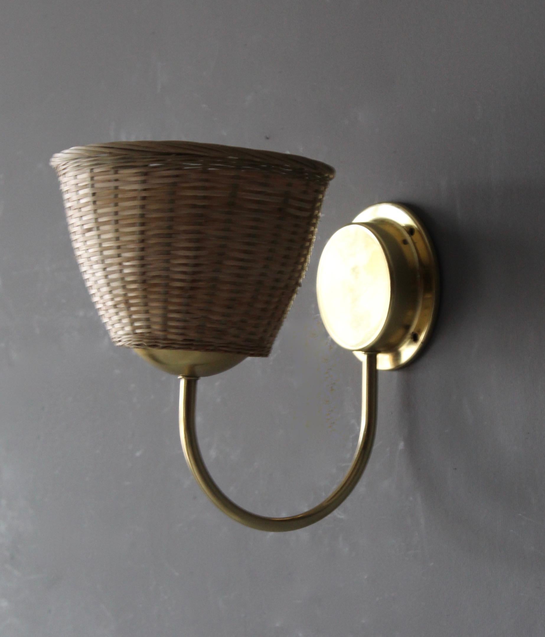 A wall light / sconce, designed and produced in Sweden, 1960s-1970s. Features brass. Assorted vintage rattan lampshade.

Takes one lightbulb on E27 socket. No stated max wattage, not UL listed. Configured for hardwire.

