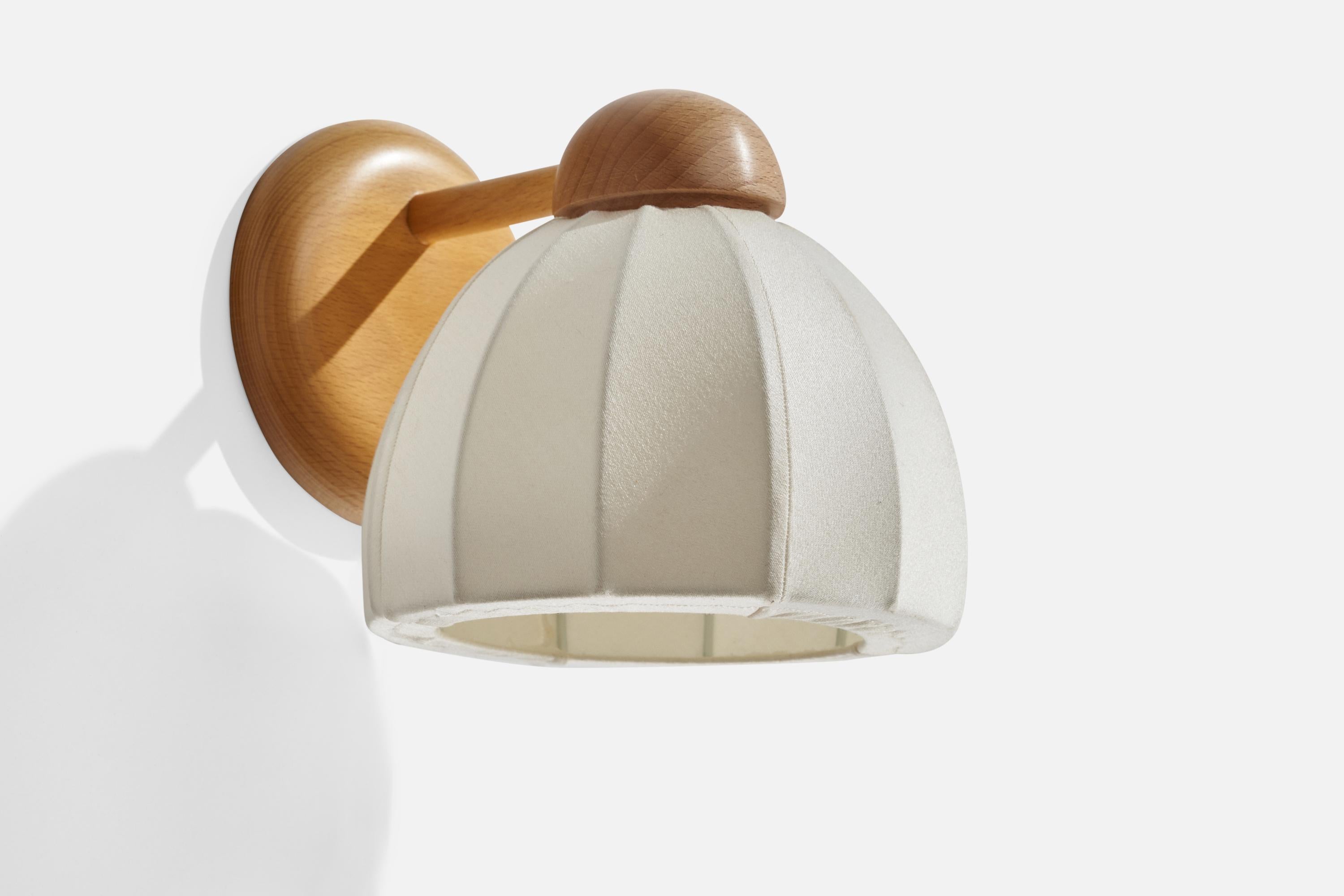 An oak and off-white fabric wall light designed and produced in Sweden, 1970s.

Overall Dimensions (inches): 8” H x 6.75” W x 6.875” D
Back Plate Dimensions (inches): 4.97” H x 0.90” D
Bulb Specifications: E-14 Bulb
Number of Sockets: 1
All lighting
