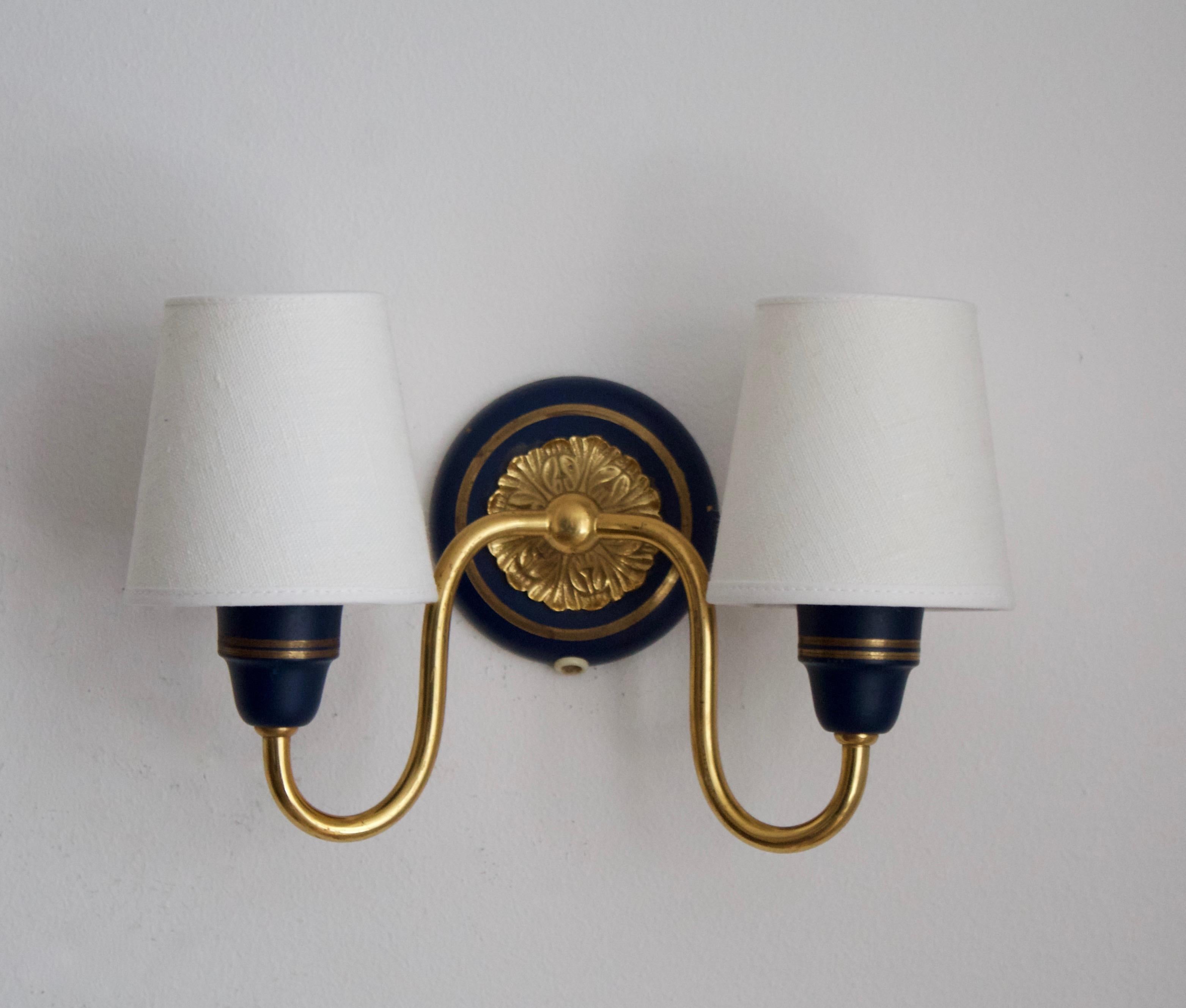 A pair of two-armed wall lights. designed and produced in Sweden, 1950s. Can also function as flush mount ceiling light.

Stated dimensions with lampshades attached.

Back plate dimension 10.8 cm.