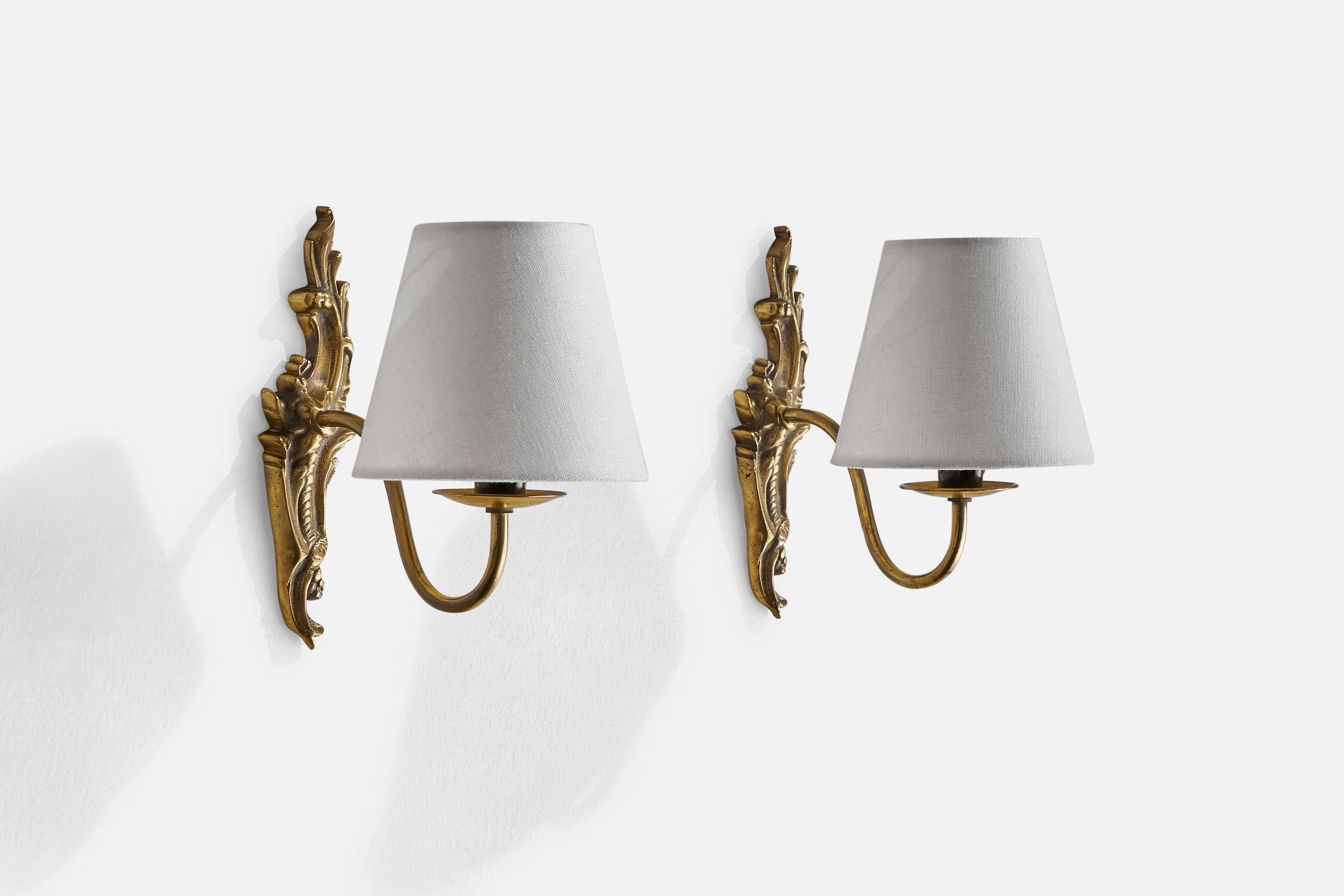 A pair of brass and white fabric wall lights designed and produced in Sweden, c. 1930s.

Overall Dimensions (inches): 8” H x 5” W x 8” D
Back Plate Dimensions (inches): n/a
Bulb Specifications: E-12 Bulb
Number of Sockets: 2
All lighting will be
