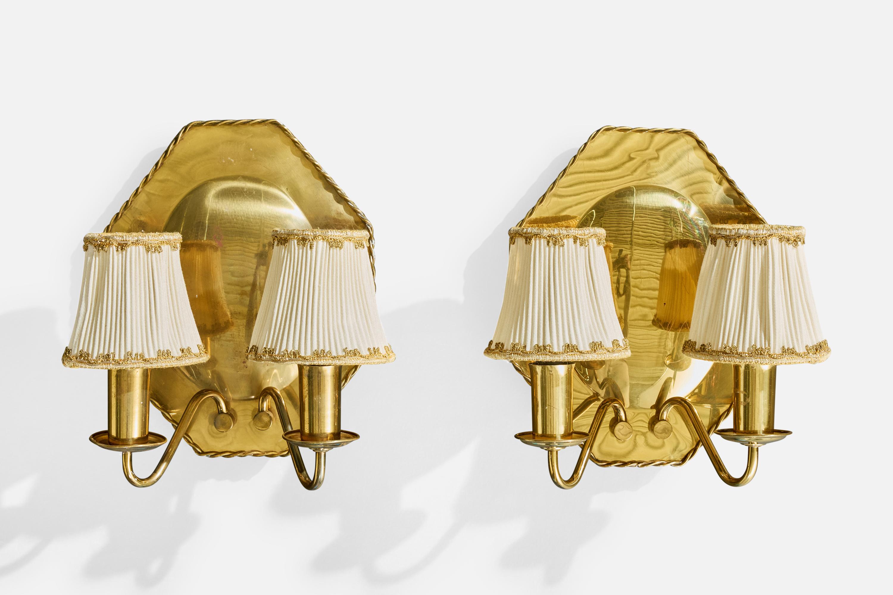 Pareja de apliques de latón y tela blanca diseñados y fabricados en Suecia, c. década de 1940.

Las pantallas y los brazos de latón presentan una ligera pátina.

Ambas placas traseras de latón tienen arañazos, decoloraciones y residuos por todas