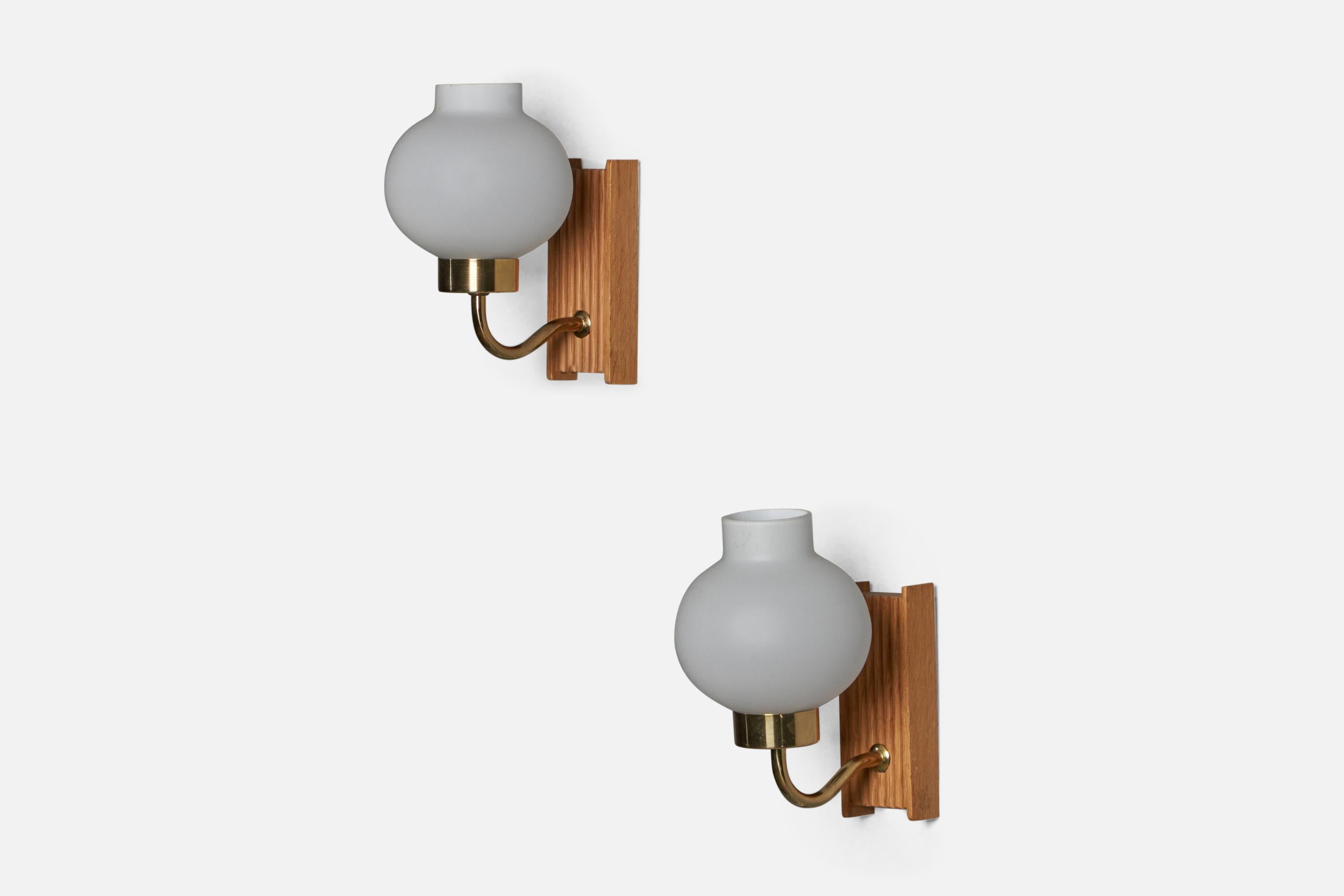 A pair of oak, brass and opaline glass wall lights designed and produced in Sweden, c. 1950s.

Overall Dimensions (inches): 8.25” H x 4.75” W x 6.75” D
Back Plate Dimensions (inches): 5.75” H x 2.3” W x 1” D
Bulb Specifications: E-14 Bulb
Number of