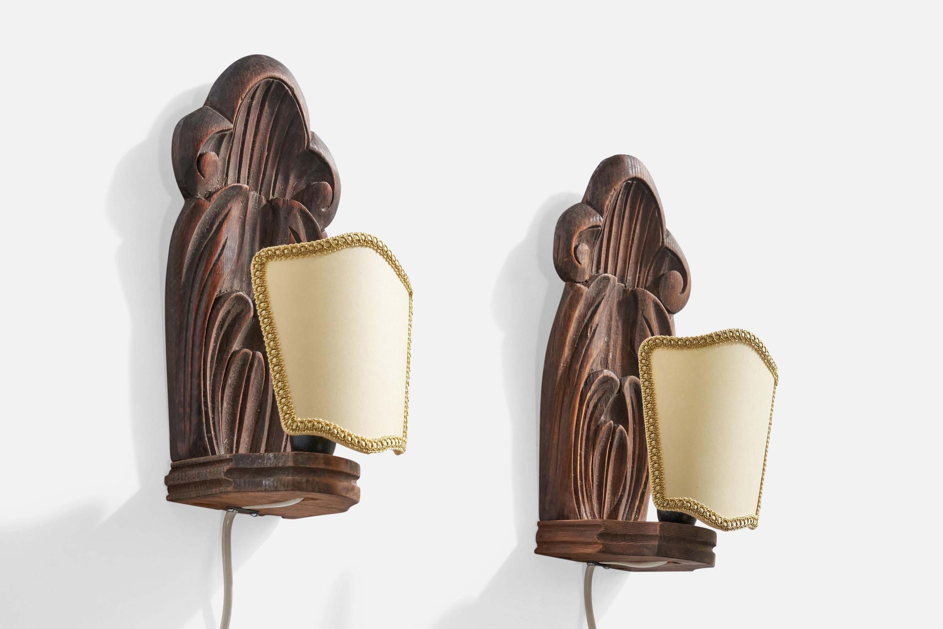 Paire d'appliques en pin foncé sculpté et tissu beige, conçues et produites en Suède, datées de 1942.

Les douilles ont été remplacées et les abat-jour sont neufs.

Dimensions globales (pouces) : 10.75