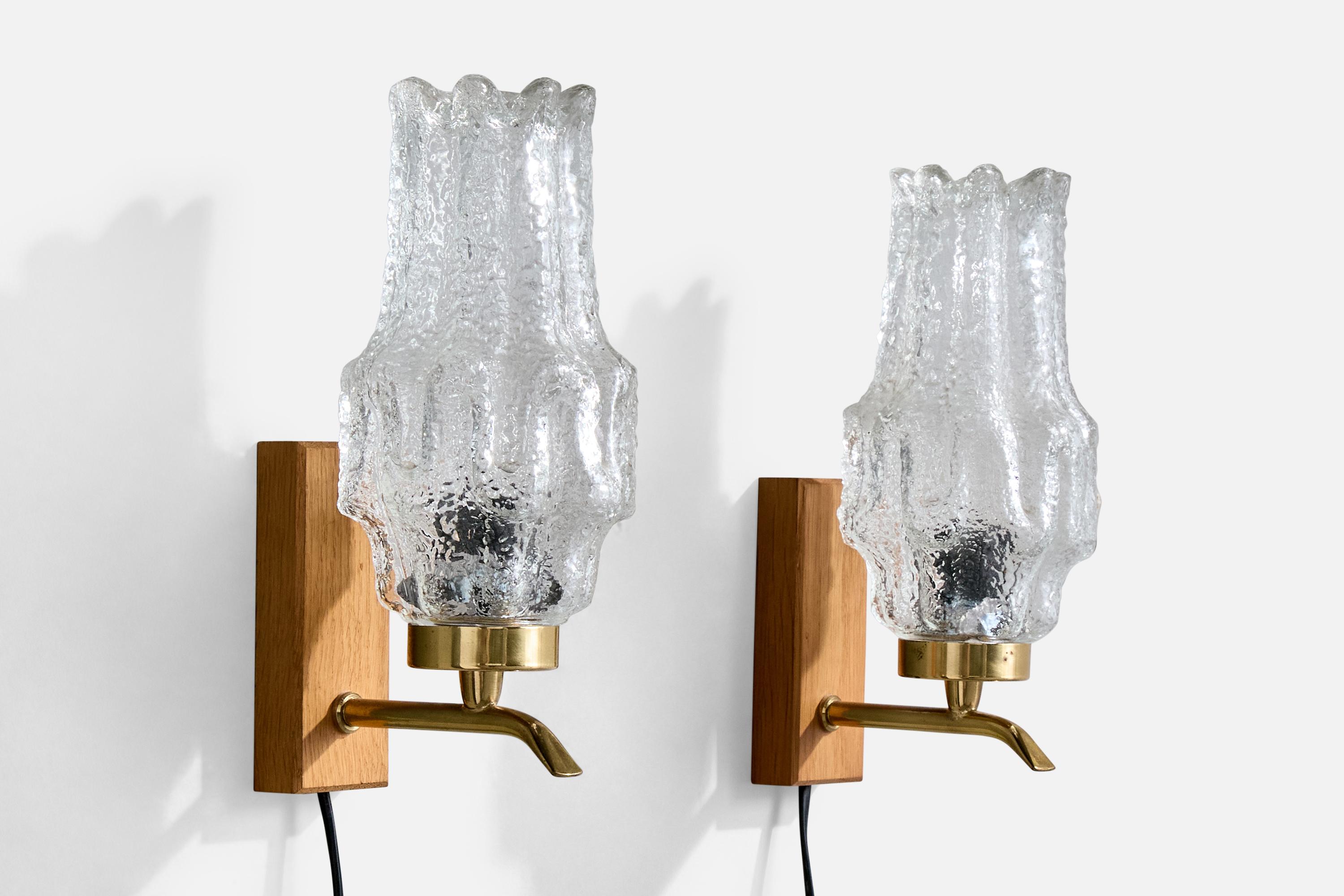 A pair of teak, brass and glass wall lights designed and produced in Sweden, c. 1950s.

Overall Dimensions (Inches): 9.2” H x 3.9” W x 5.25“ D

Back Plate Dimensions (Inches): 4.6” H x 1.825“ W x .9” D

Bulb Specifications: E-14

Number of Sockets
