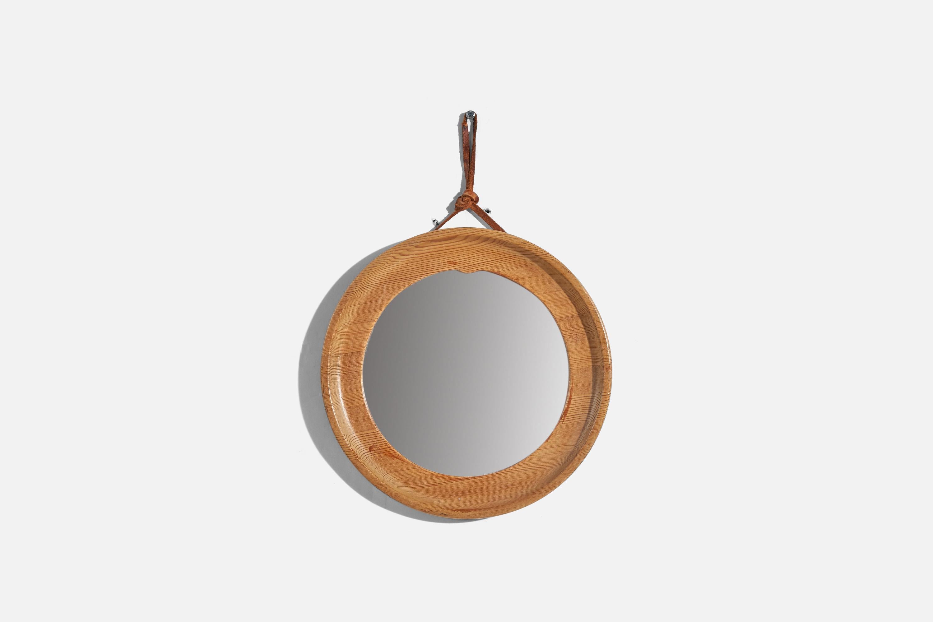 A pine and leather wall mirror designed and produced in Sweden, 1970s.
 