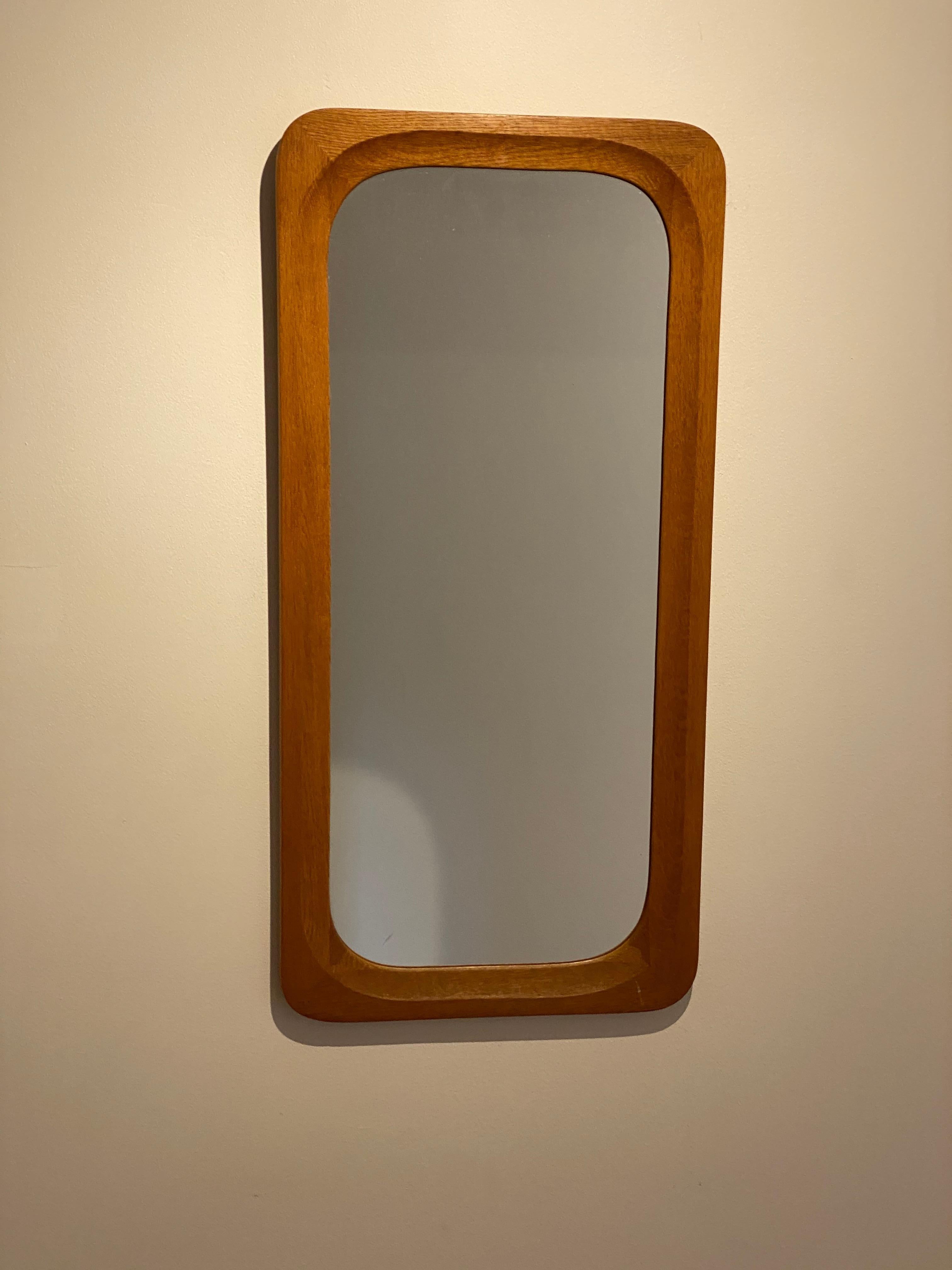 A stained oak mirror, glass with a finely sculpted teak frame wrapping the glass in a rounded form.

Other designers of the period include Hans Wegner, Josef Frank, Finn Juhl, George Nakashima and Arne Jacobsen.