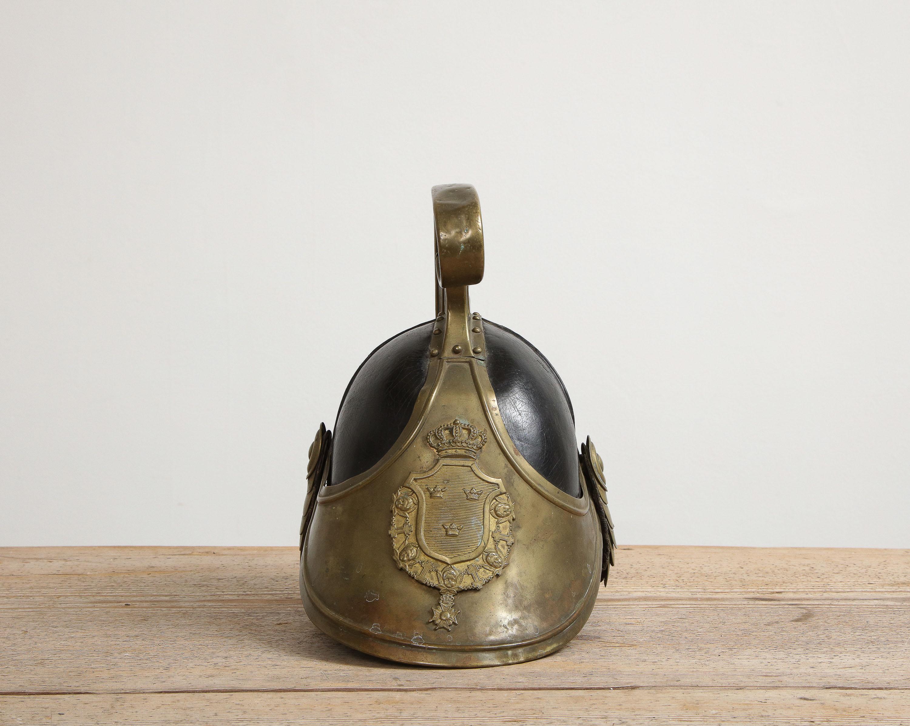 A Swedish dragoon helmet, equipment utilized by a member of a ceremonial cavalry regiment, origin: Sweden, circa 1800, all original leather and brass plate 

This helmet is adorned with a brass plate containing a coat of arms with the national
