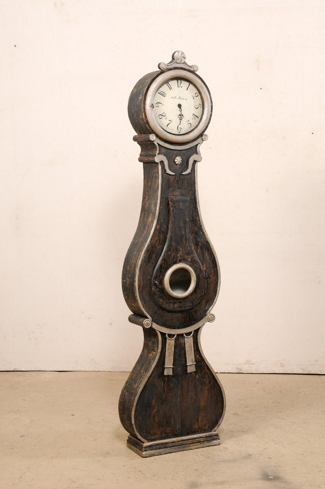 Pendule suédoise Fryksdahl, avec de belles décorations, datant du début du 19e siècle. Cette horloge antique Fryksdahl de Suède est ornée de nombreux accents décoratifs qui rehaussent et accentuent la forme de cette horloge. Le cimier ou couronne