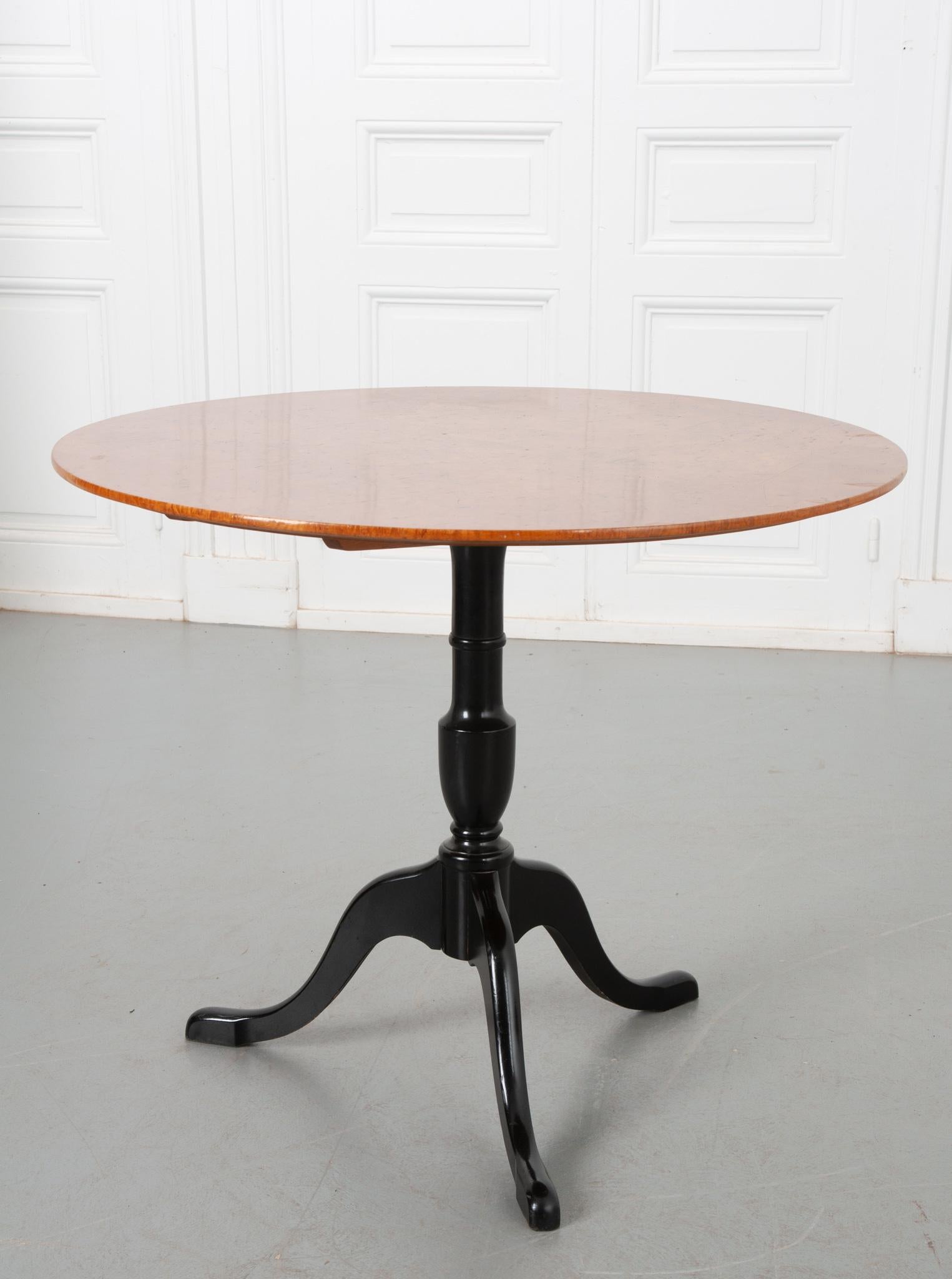 An eye-catching tilt-top table from Sweden, circa 1900. The top is made of vibrant birch that beautifully contrasts with the supper foot ebony base. This table has the ability to be stored away when not in use thanks to the tilting mechanism that