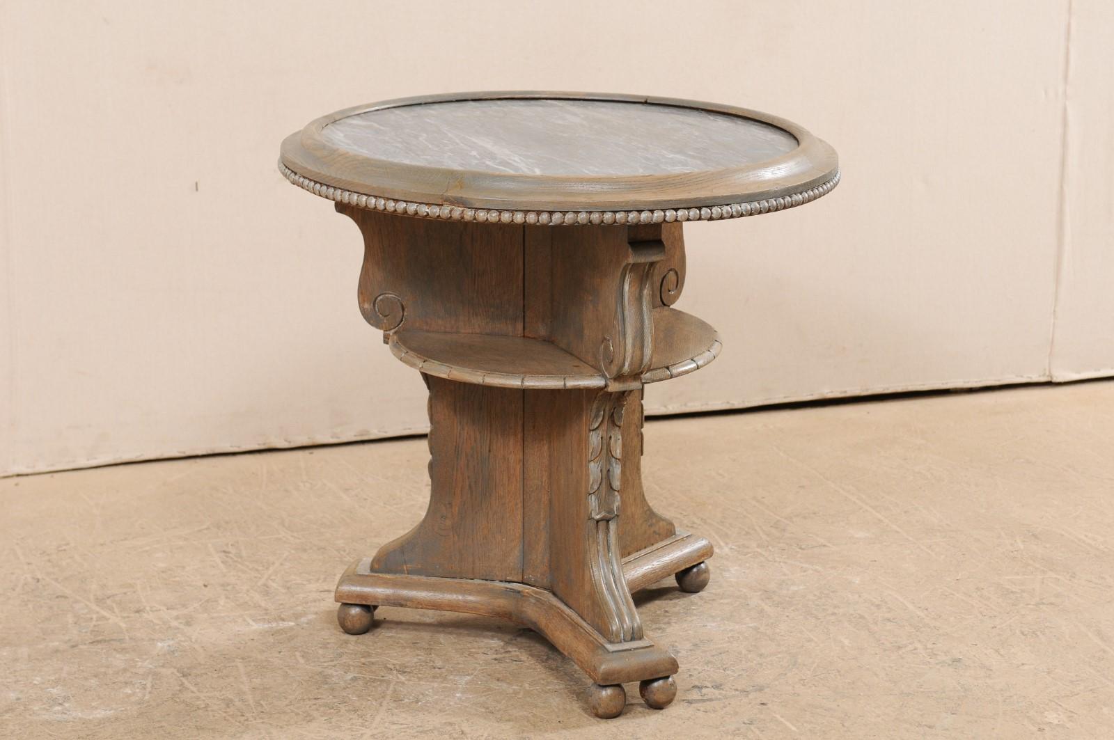 A Swedish round-shaped occasional table with marble top from the early 20th century. This antique guéridon style table from Sweden features a round-shaped marble top which has been set within a wood-rimmed surround with delicately carved beaded