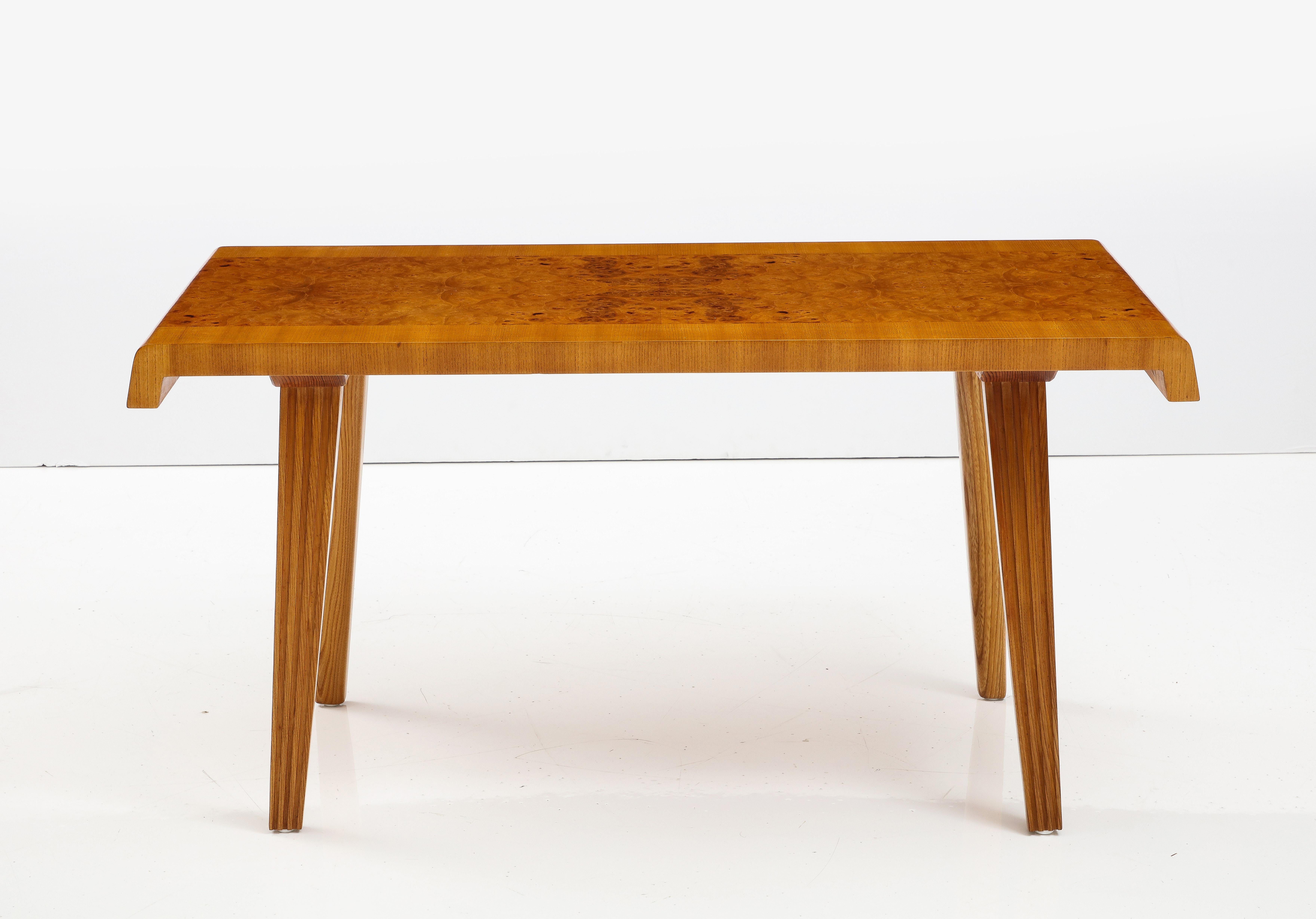 A Swedish Modern elm and elm root table, probably by Reiners Mjölby, Circa 1940s, the rectangular top with a rounded end, the center with an elm root veneer cross-banded with elm raised on rectangular tapered and fluted legs.