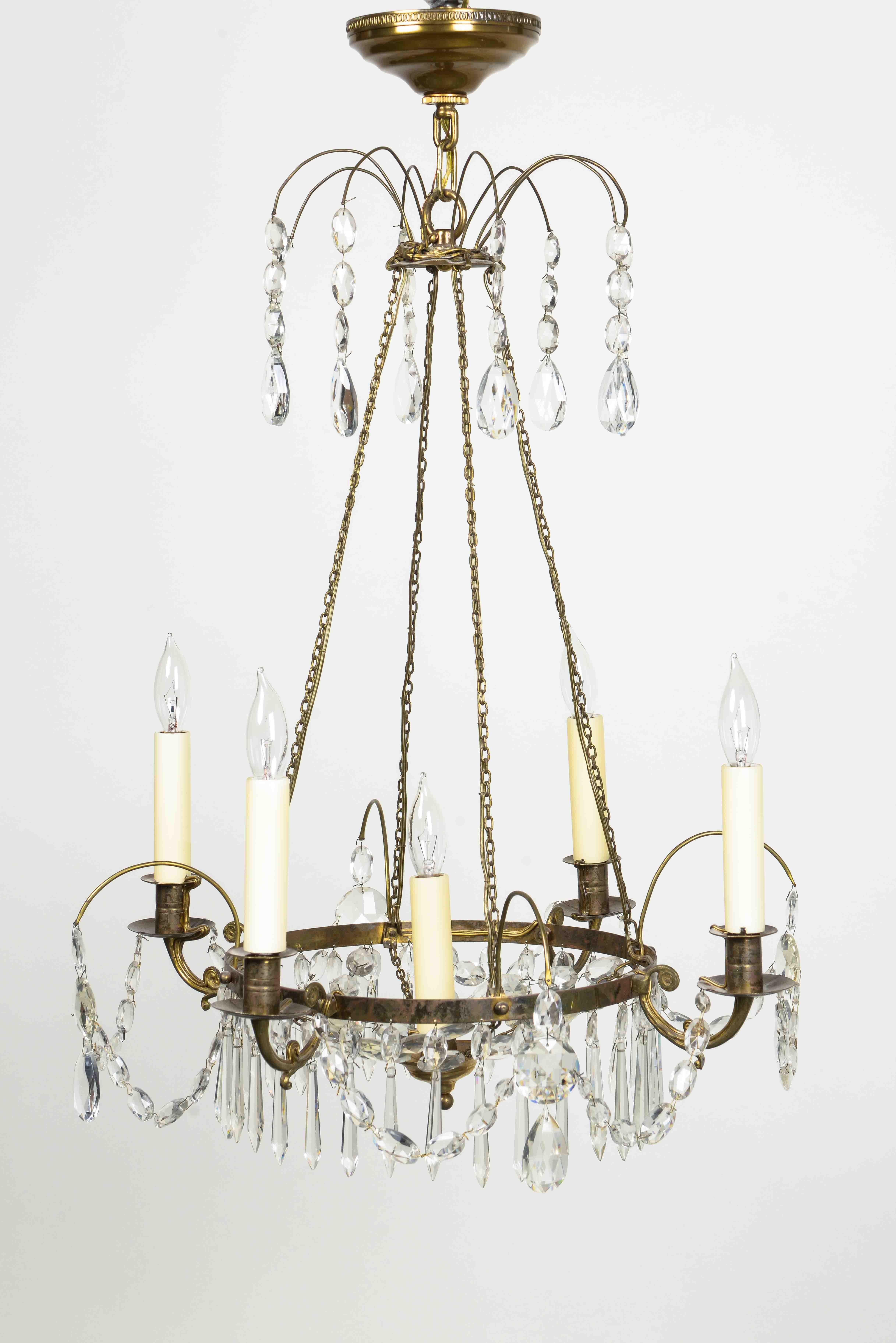 With a five outscrolled electrified candlearms issuing from a bronze ring hung with crystal beaded swags and drop pendants, hung from four chains suspended from a disc issuing arched cut glass pendants; with canopy. Fitted with five candelabra bulb
