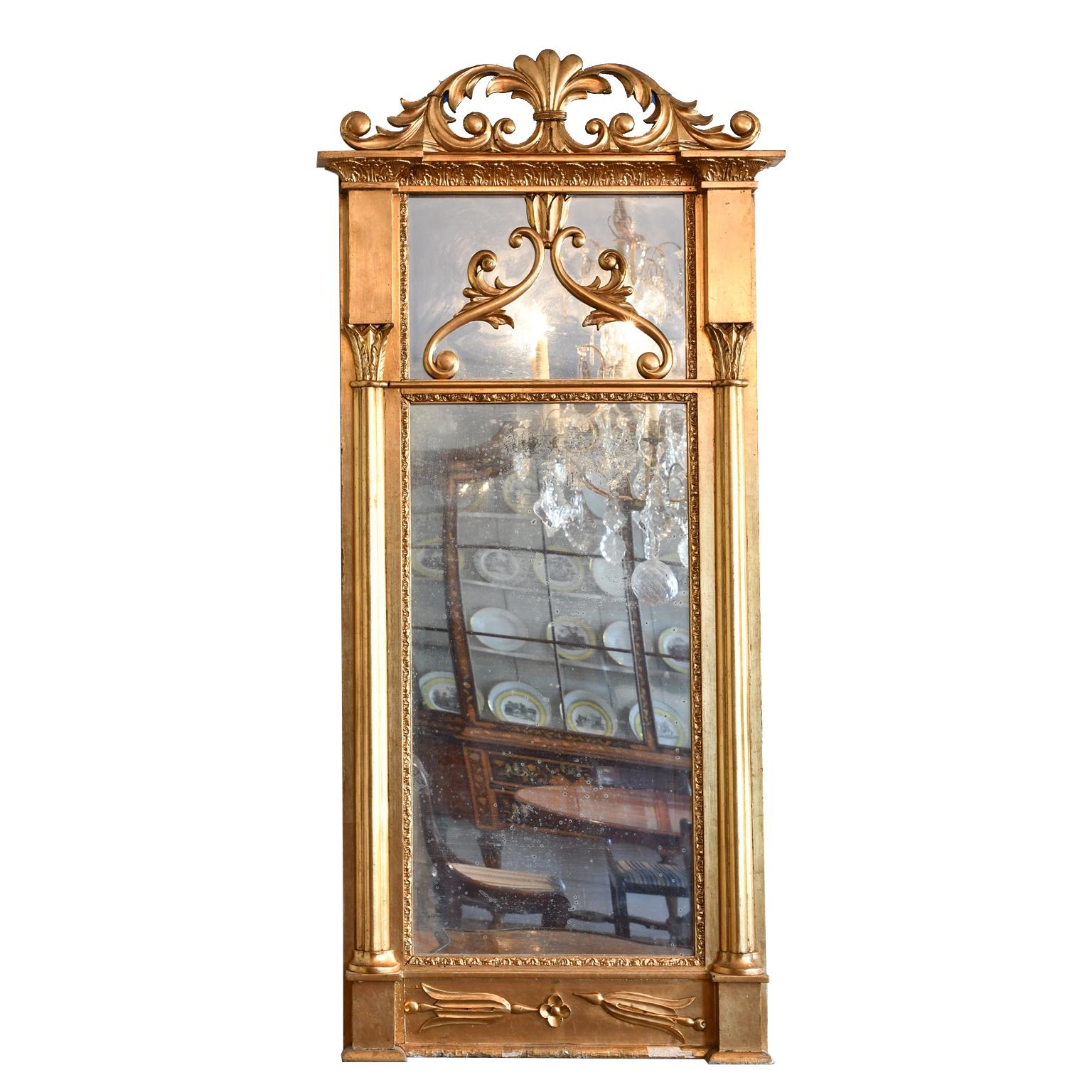A lovely Karl Johan mirror in giltwood with carved and scrolling acanthus foliage above cornice. Main rectangular mirror plate is flanked by pilasters with acanthus-carved capitals, and surmounted by a smaller mirror plate that is decorated with 