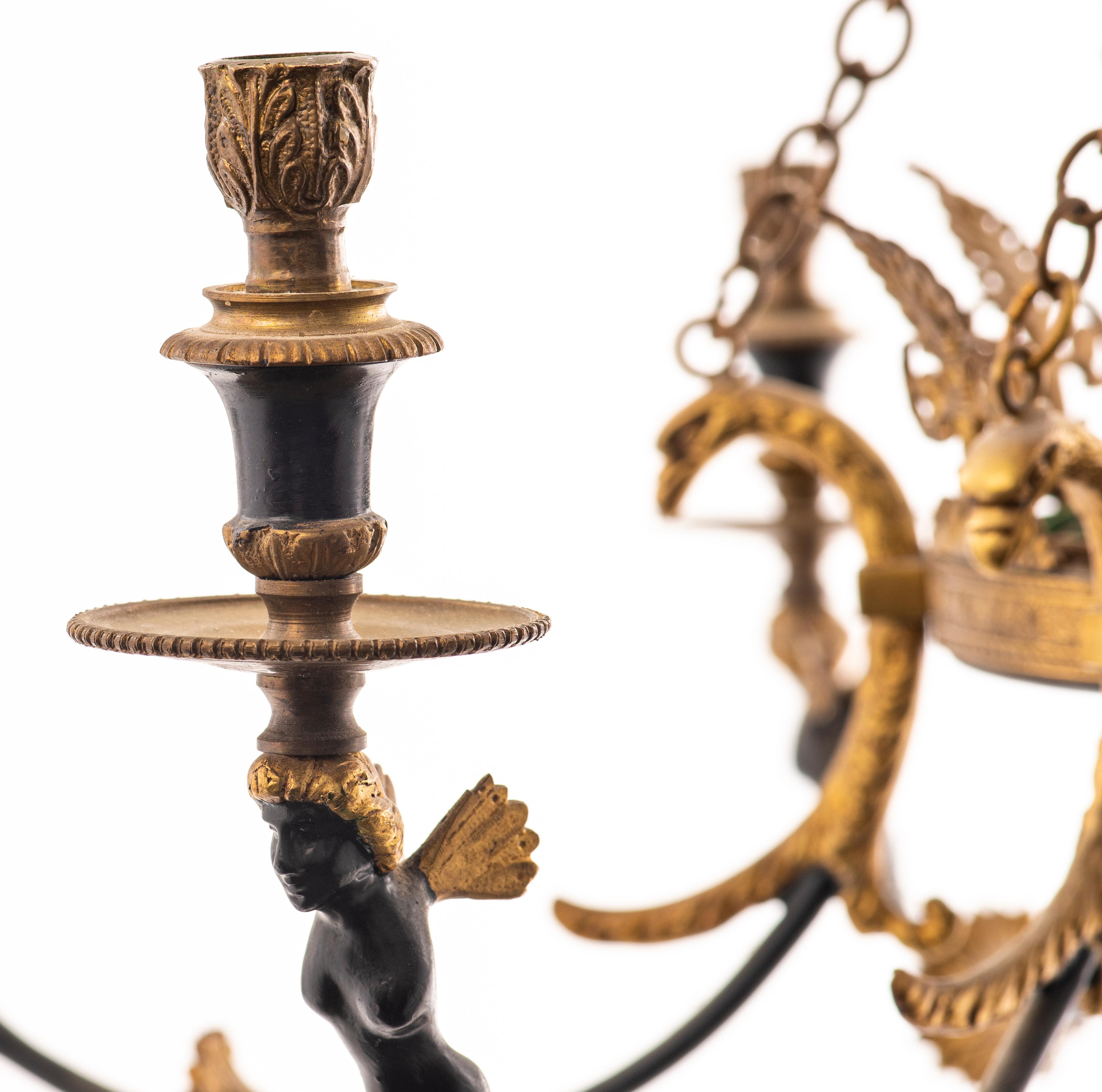 Swedish Empire style gilt and patinated bronze six-light chandelier, the arms with eagle and winged figures around a foliate accent, the standard with palmette and star motifs.
Dimensions: 25” height x 29.5” diameter.
  