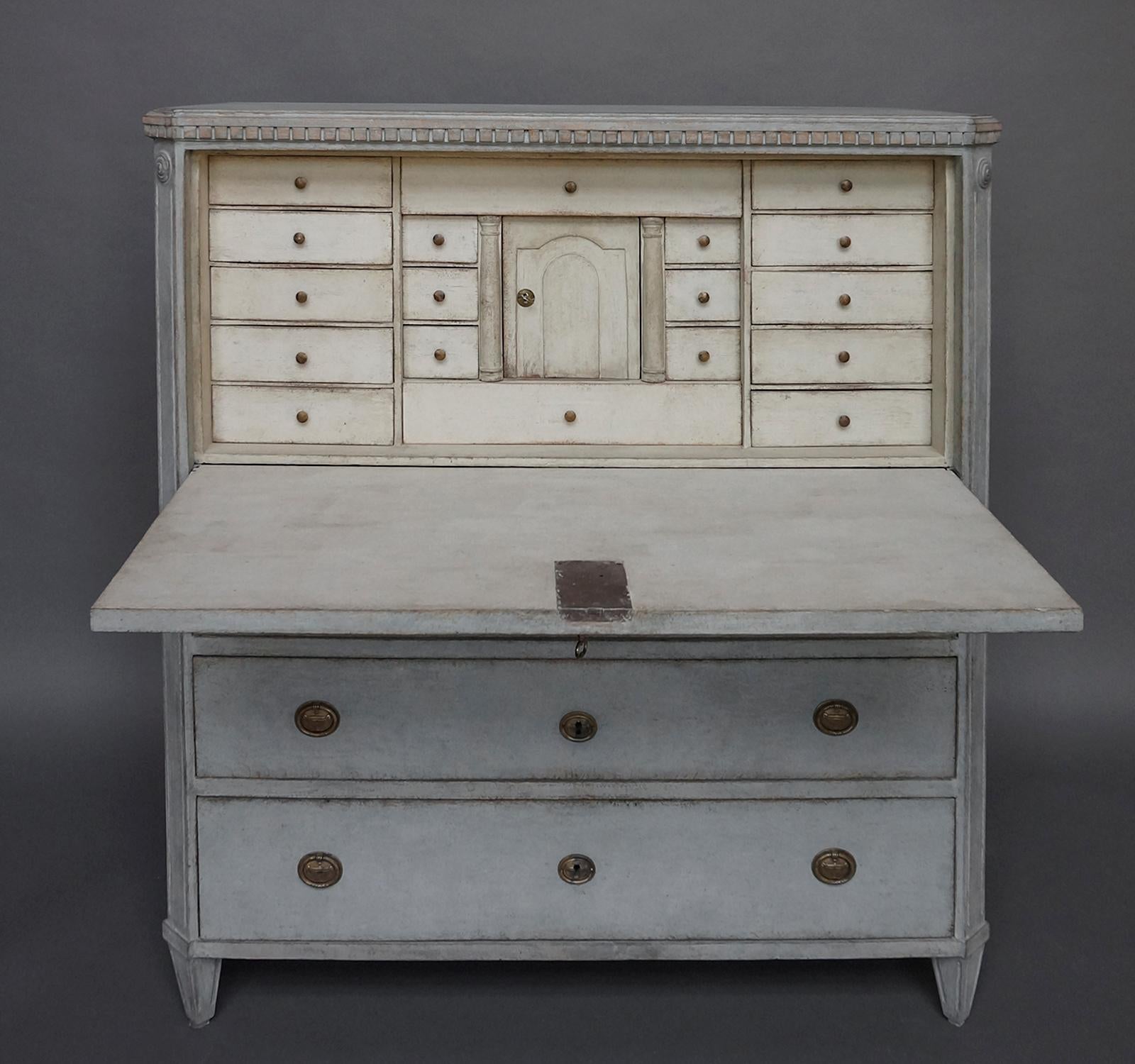 Swedish writing desk, circa 1820, with eighteen small drawers and a locking compartment in its fitted interior. Three full width drawers with molded brass pulls. Dentil molding around the top, canted corners, and tapering feet.