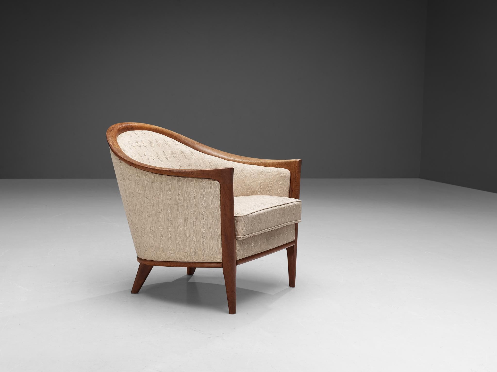 Armchair, teak and fabric, Sweden, 1950s.

This easy chair features its original beige upholstery. The unique lines and curves of the design are striking and the tapered wooden legs complement its shape beautifully. Highly comfortable and