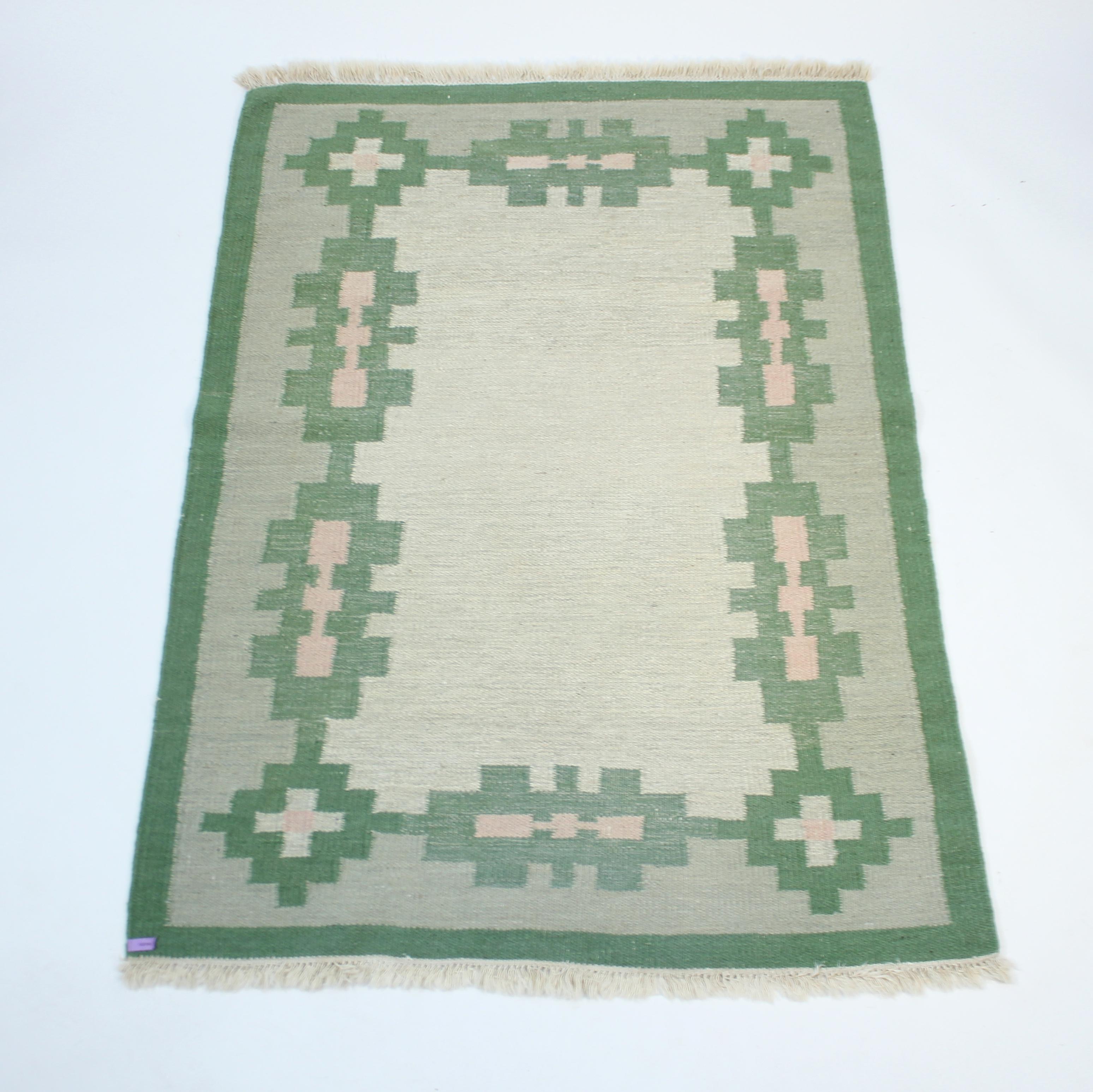 Tappeto svedese a trama piatta Röllakan degli anni '1960 di designer sconosciuto. Il colore principale è il verde in diverse tonalità con una varietà di motivi e forme in rosa, beige e blu su un fondo/base verde e beige. Pulito di recente da