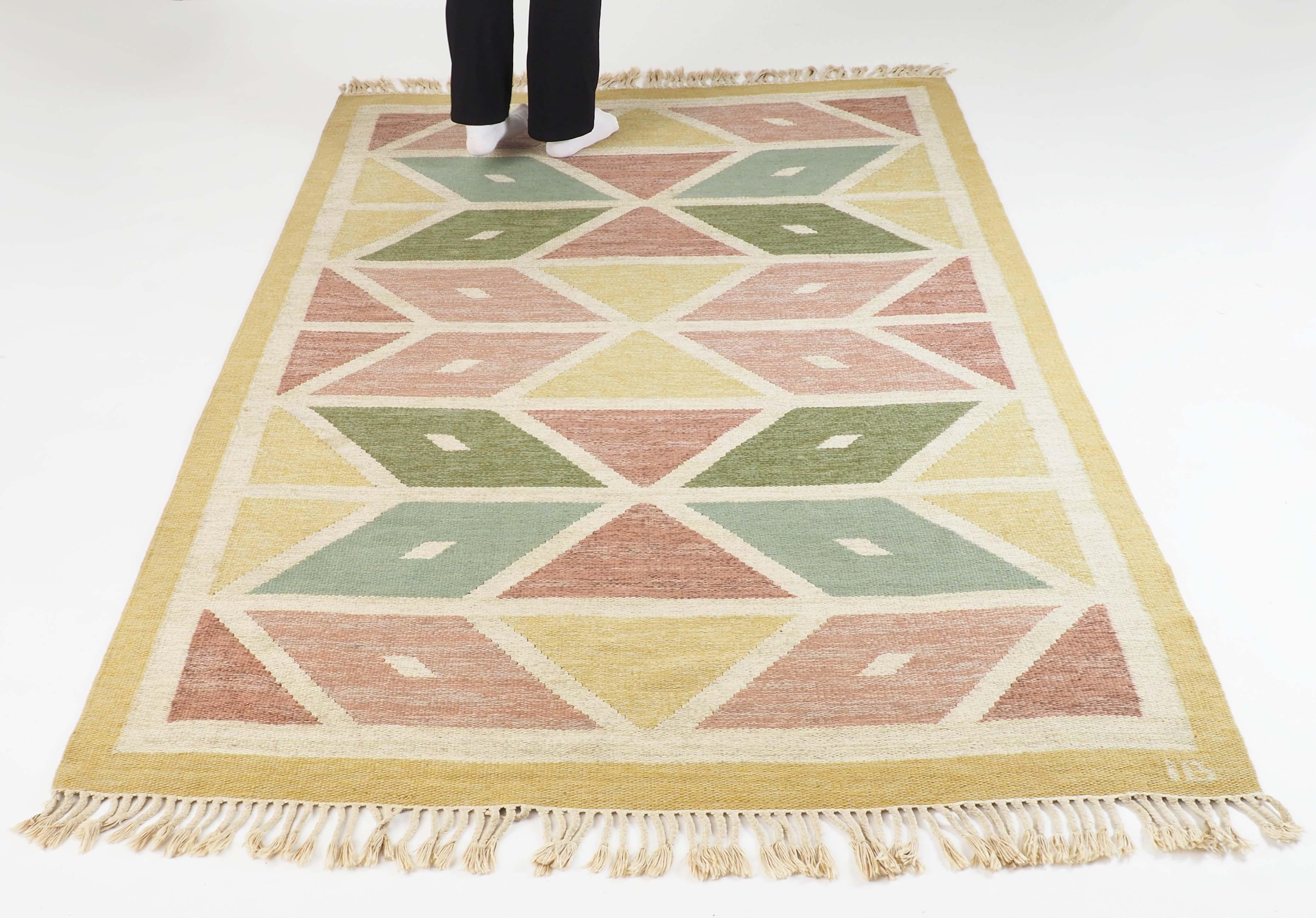 Swedish flat-woven rug in wool. Handmade in the 1950s and signed IB by the artist. Diamond shaped pattern in a strict geometrical design.