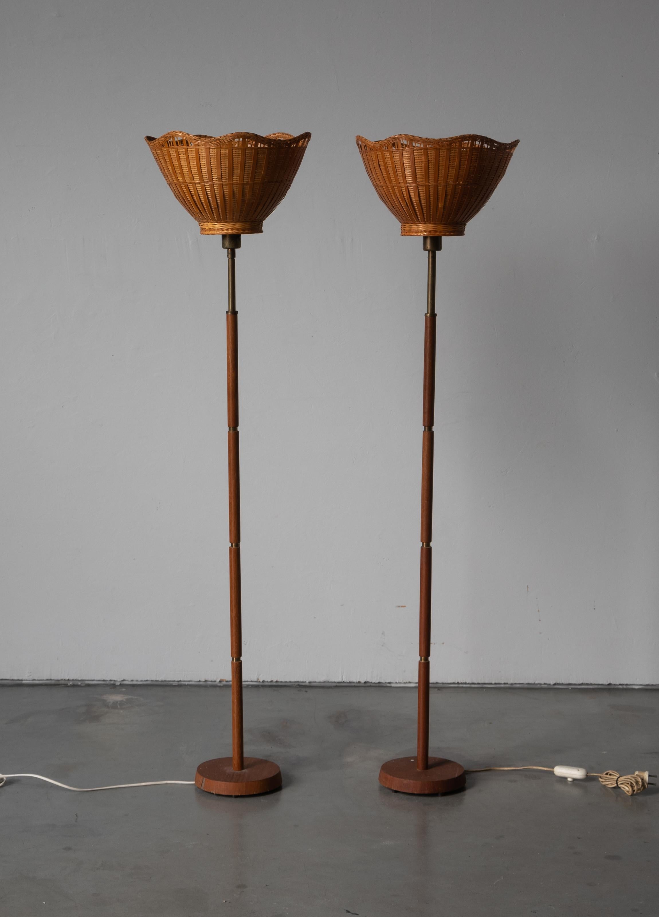 A pair of floor lamps, designed and produced in Sweden, 1950s. In brass and teak. Assorted vintage rattan lampshades.

  