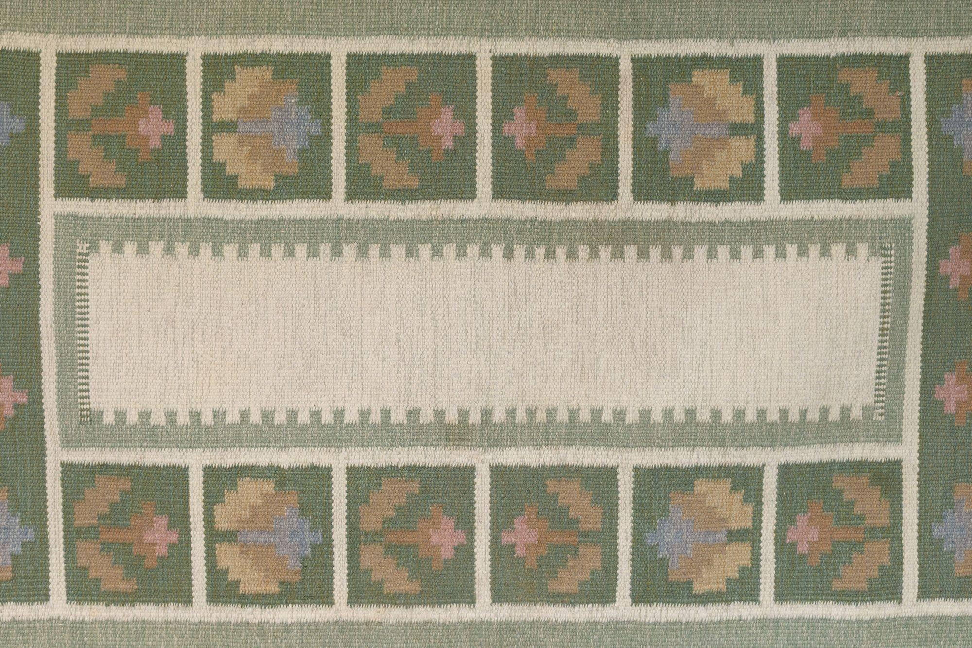 Piccolo kilim svedese di metà secolo nei toni del verde e del crema con bordo floreale. Svezia, circa 1960. Tutti i nostri tappeti sono sottoposti a un processo di pulizia professionale. Tuttavia, a causa della loro età e della loro vita precedente,