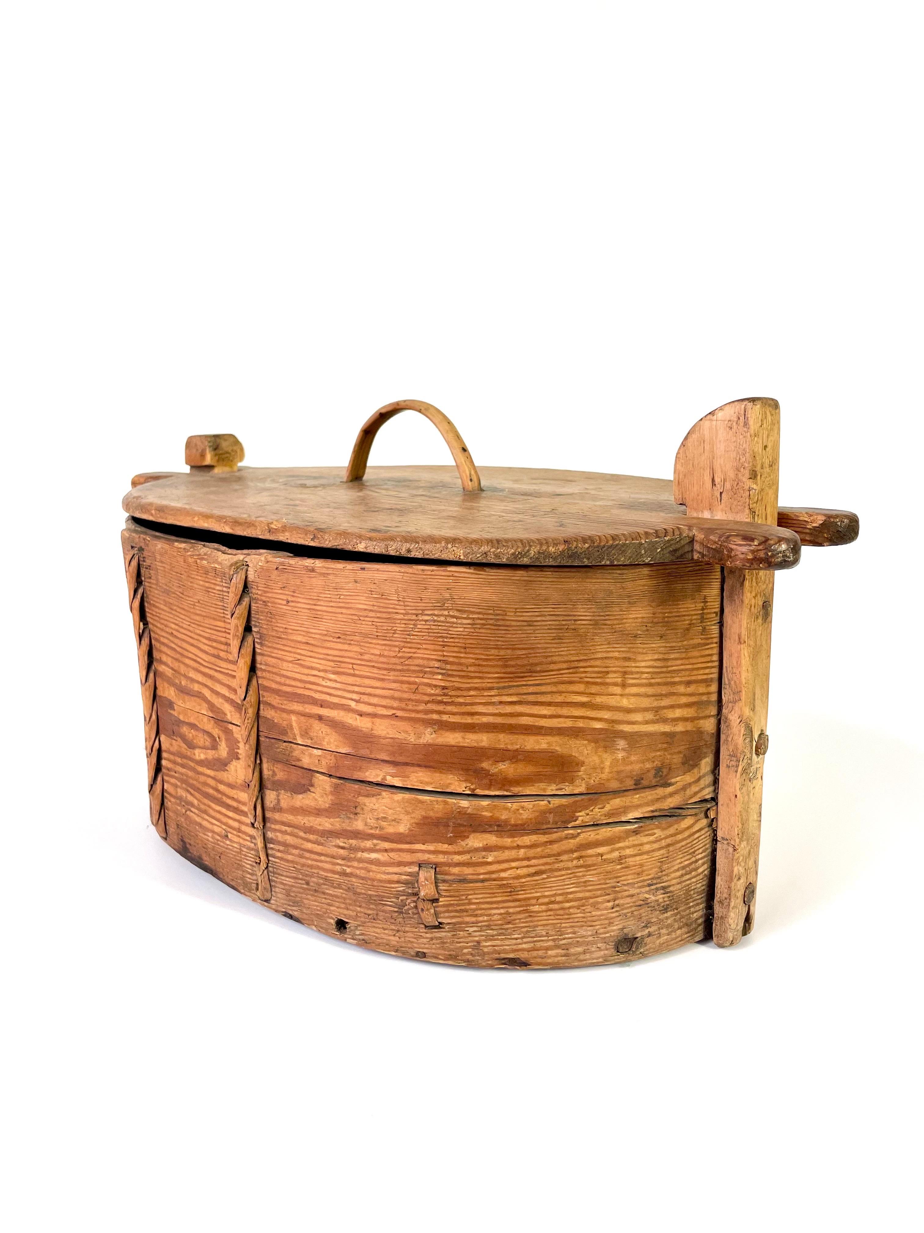 This is a Swedish wooden box, so-called svepask, from the second half of the 19th century.
This type of vessel was used when the daily provisions were carried out to the fields or to the forest.
The lid was used as a cutting board.

It comes made of