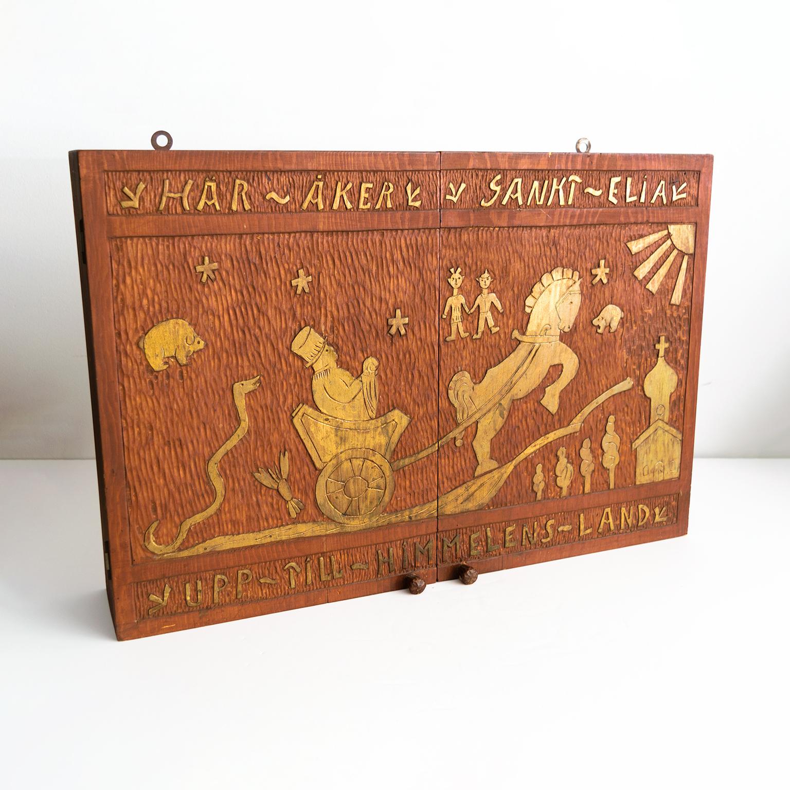 Swedish mid-20th century Folk Art wall cabinet of carved pine, painted in “mahogany” red. The motif depict a man in a horse pulled carriage, various animals including a snake, crayfish, pig and bear. The inscription translated to English reads “Here