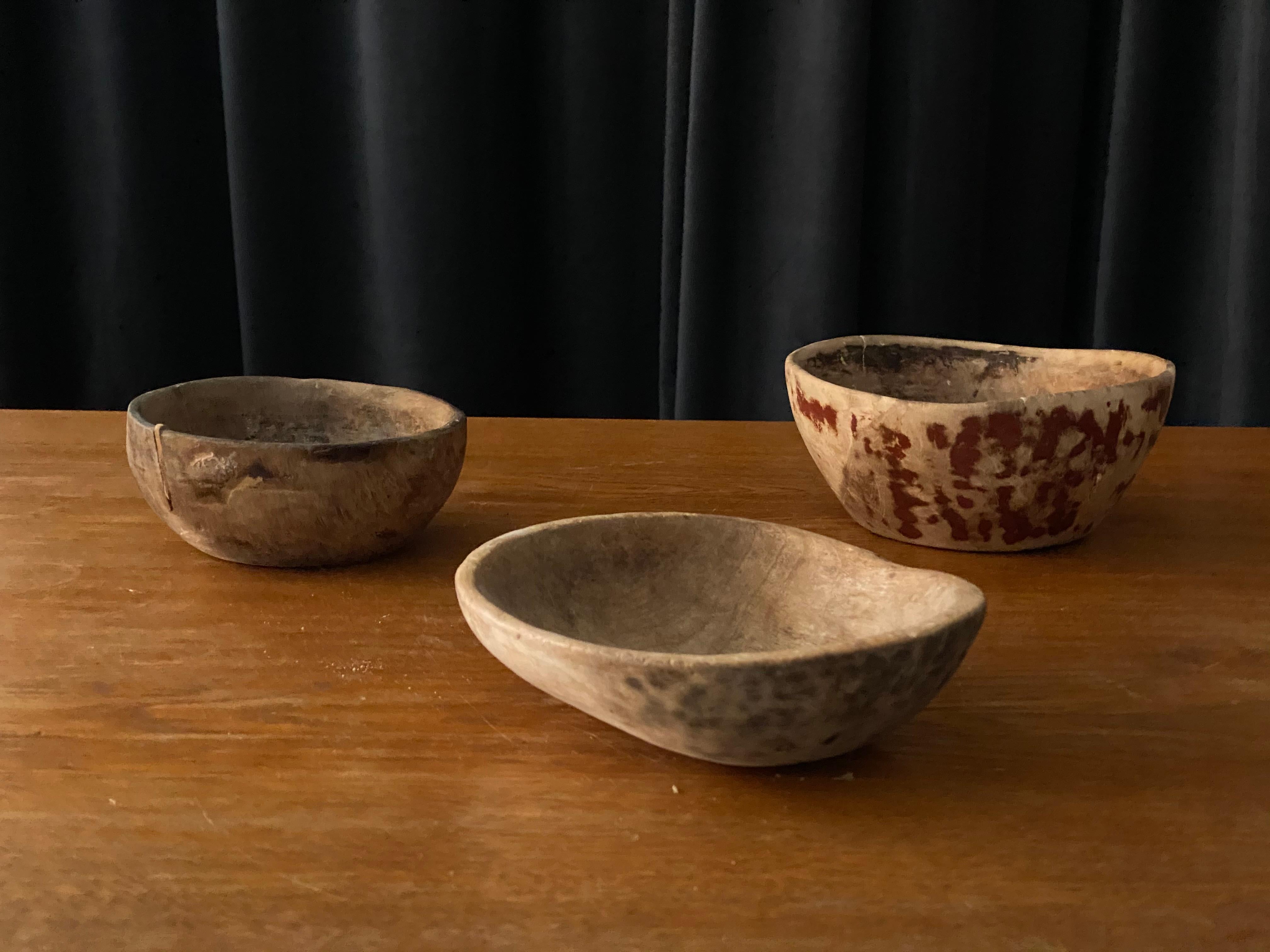 A set of three antique, unique organic farmers wooden bowls. With highly appealing patina, Produced in Sweden, 19th century. One features a beautiful old repair. One has traces of old red color. One signed and dated.
 
Height, tallest to lowest