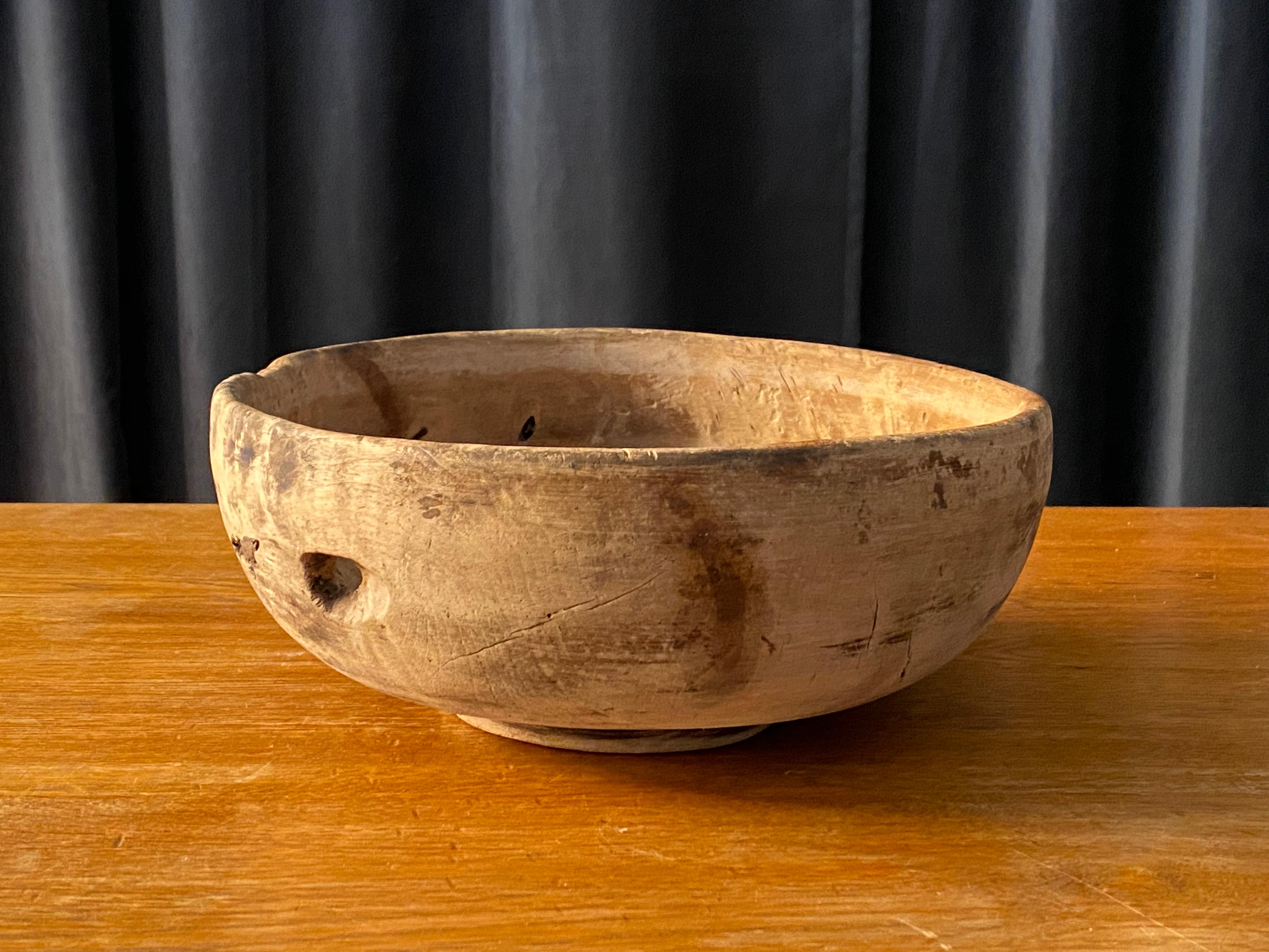 An antique and unique large organic and early farmers wooden bowl. Signed PSS.
Produced in Sweden, 18th century. A knothole creates a beautiful void in the wood, adding to the sculptural appeal of the work. 
 
  