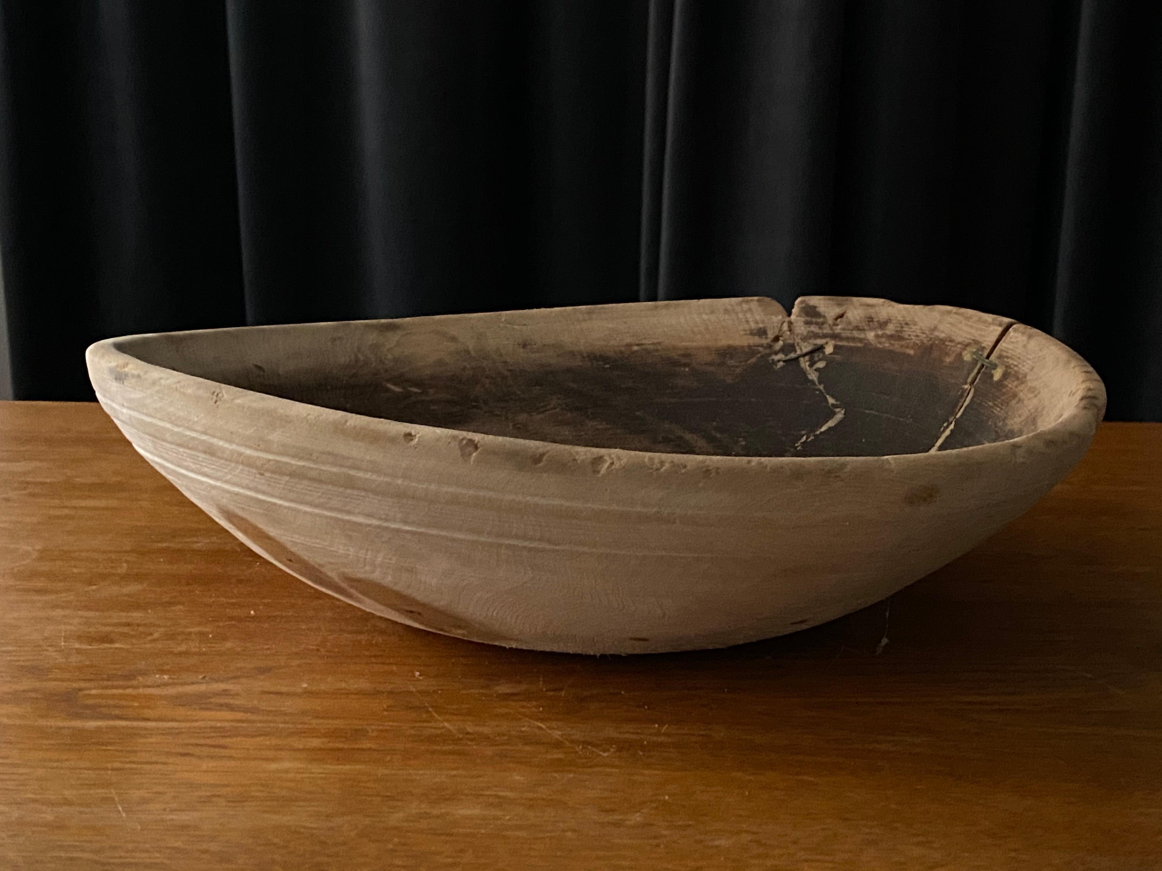 An antique, unique organic and large farmers wooden bowl. With highly appealing patina, Produced in Sweden, 19th century. Features old metal wire repairs. 
 