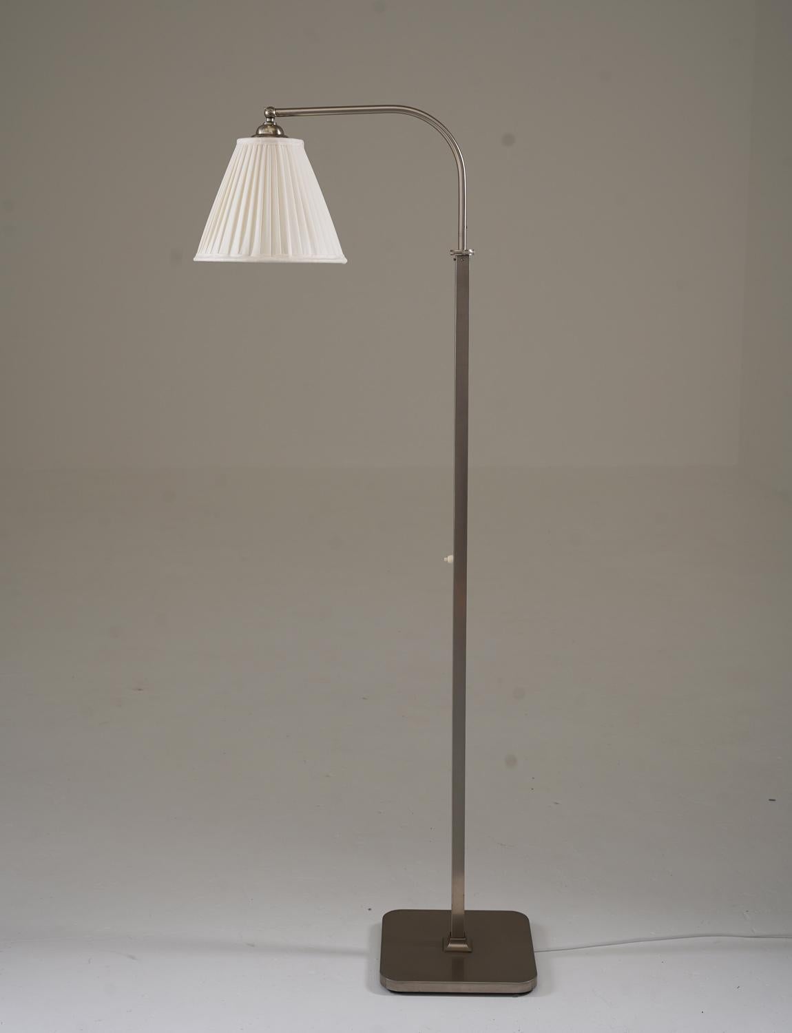 Elegante lámpara de pie de los años 30, fabricada en Suecia, de latón niquelado mate. Presenta una pantalla de seda plisada a mano recién cosida. La altura es regulable de 145 a 165 cm (de 57,1