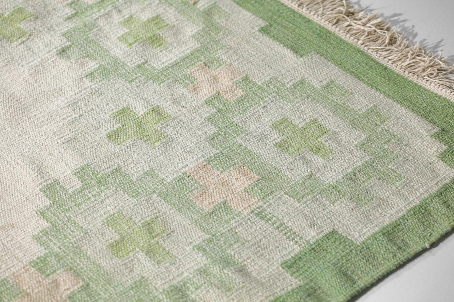 Très grand tapis scandinave des années 60. Technique de tissage à plat (röllakan), laine sur lin. Motifs géométriques traditionnels dans les couleurs vert, blanc et beige. Tissé à la main en Suède dans les années 50 et 60. Excellent état vintage