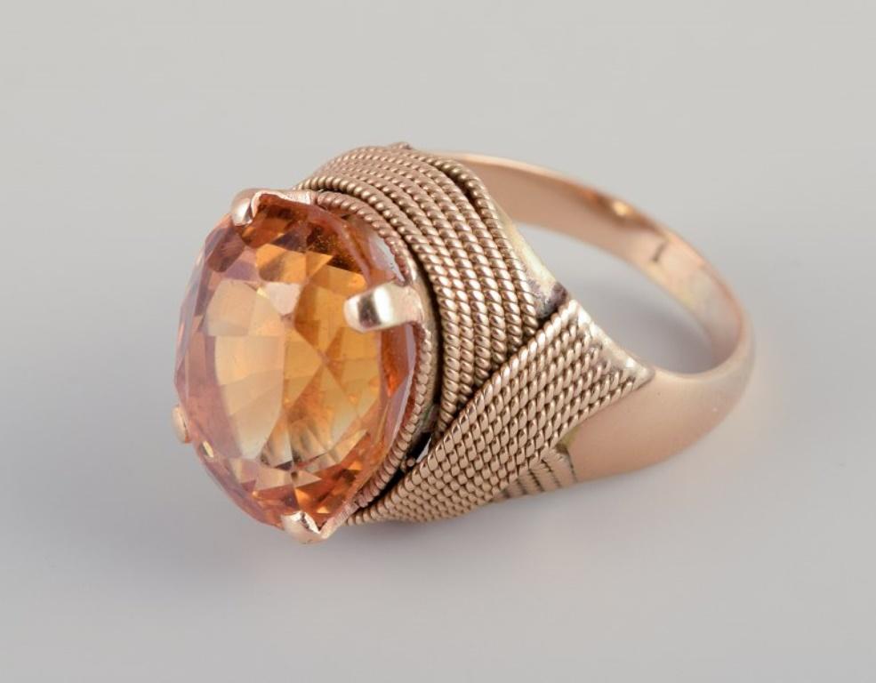 Schwedischer Goldschmied. Großer 18-Karat-Cocktailring mit facettiertem bernsteinfarbenem Citrin. Dekoration mit Bändern.
Aus der Mitte des 20. Jahrhunderts.
Markiert 18K.
Perfekter Zustand.
Gewicht: 8,5 Gramm
Abmessungen: 16 mm / US Größe 5
