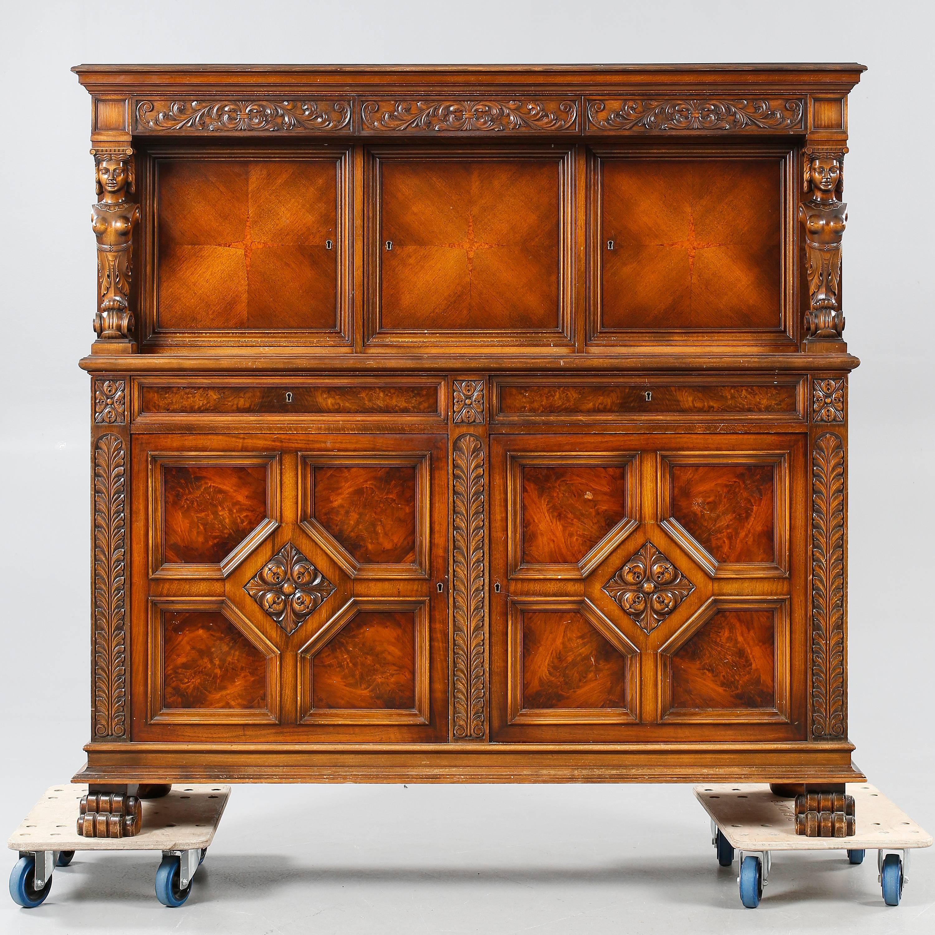 Swedish Art Deco era Gothic Revival storage or bar cabinet with carved female figures.
Crafted in the 1930s. With five locking storage compartments. With five drawers. Interior with adjustable/removable shelves. In excellent original condition with