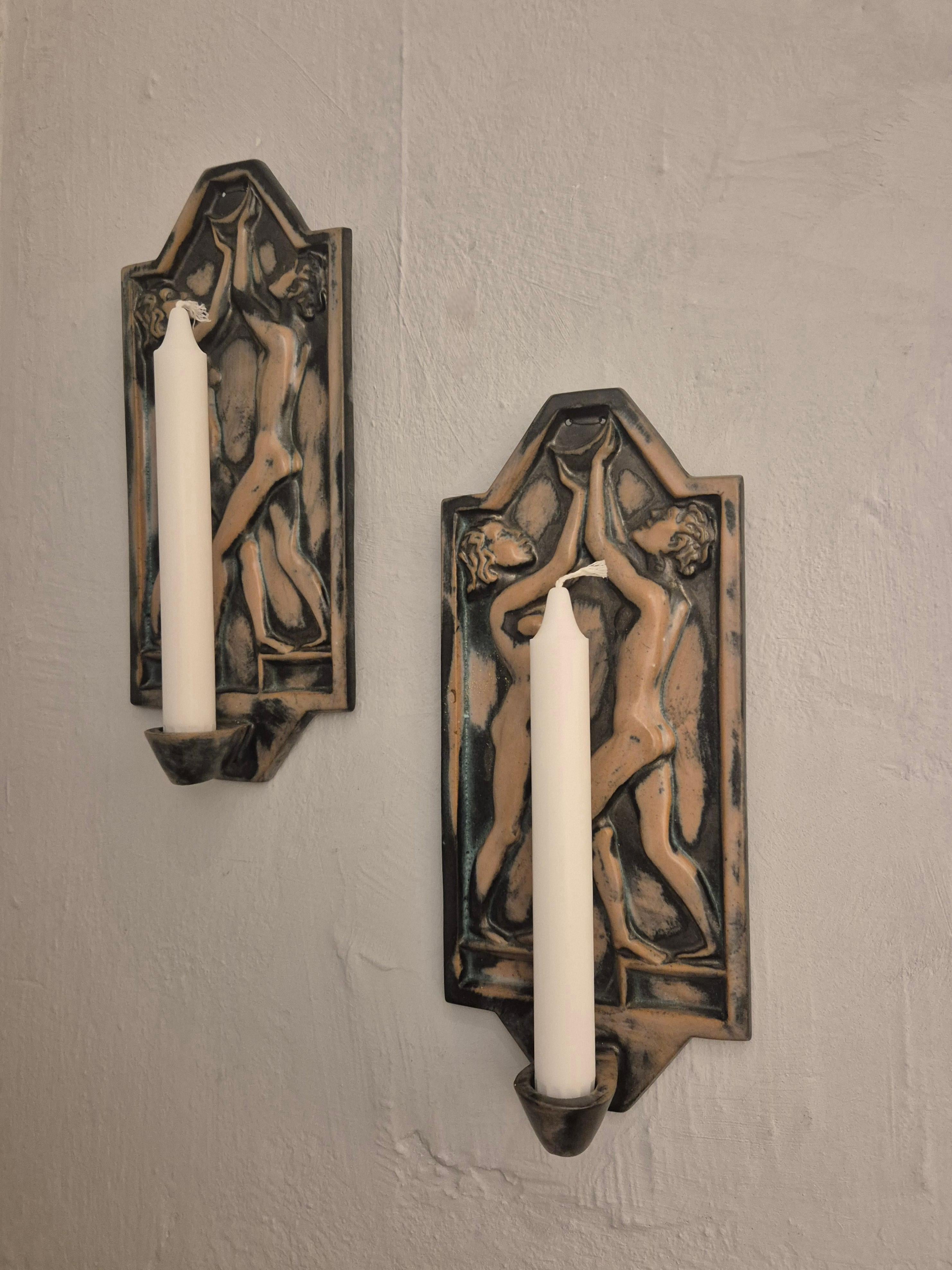 Une rare paire de bougeoirs muraux du fabricant suédois fondé en 1925, Gabriel Keramik.

Magnifique décor d'un homme et d'une femme cherchant à décrocher la lune. Fabriqué en faïence avec une glaçure brune/grise. 

Marqué a tergo : GABRIEL 
