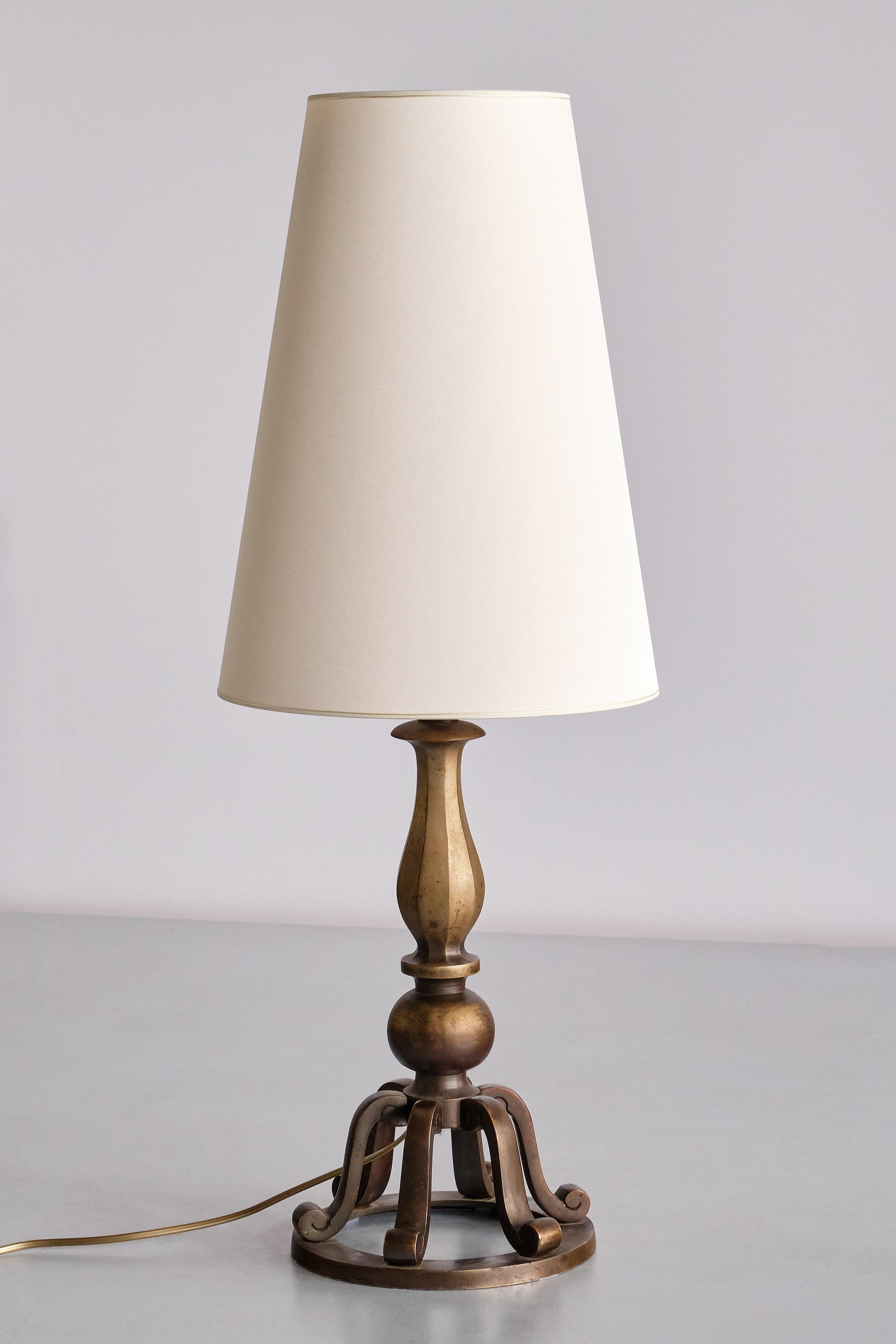 This striking table lamp was produced by the C.G. Hallberg company in the 1930s. The decorative design is characterized by the bell-shaped body in solid patinated brass. Circular base on which six curved components form a bell shape. The upper part