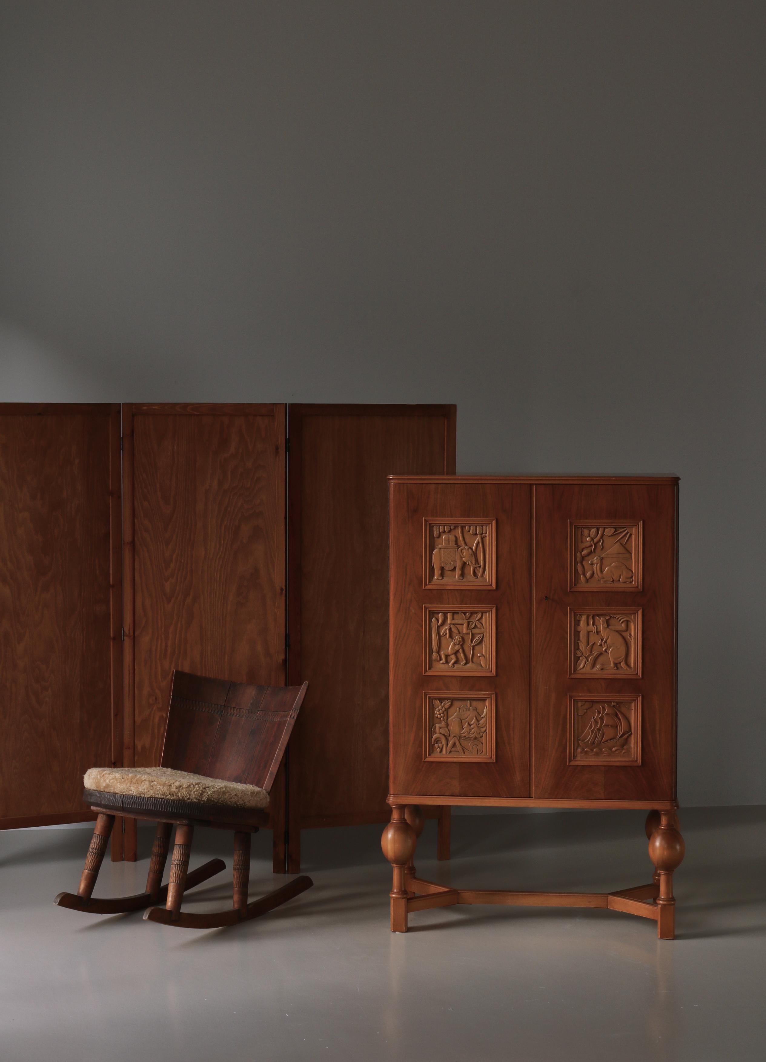 Magnifique armoire suédoise Grace du designer suédois Eugen Höglund avec 6 magnifiques panneaux sculptés à la main représentant divers animaux et paysages en bois fruitier et en hêtre. Le meuble dispose de deux étagères intérieures et de deux