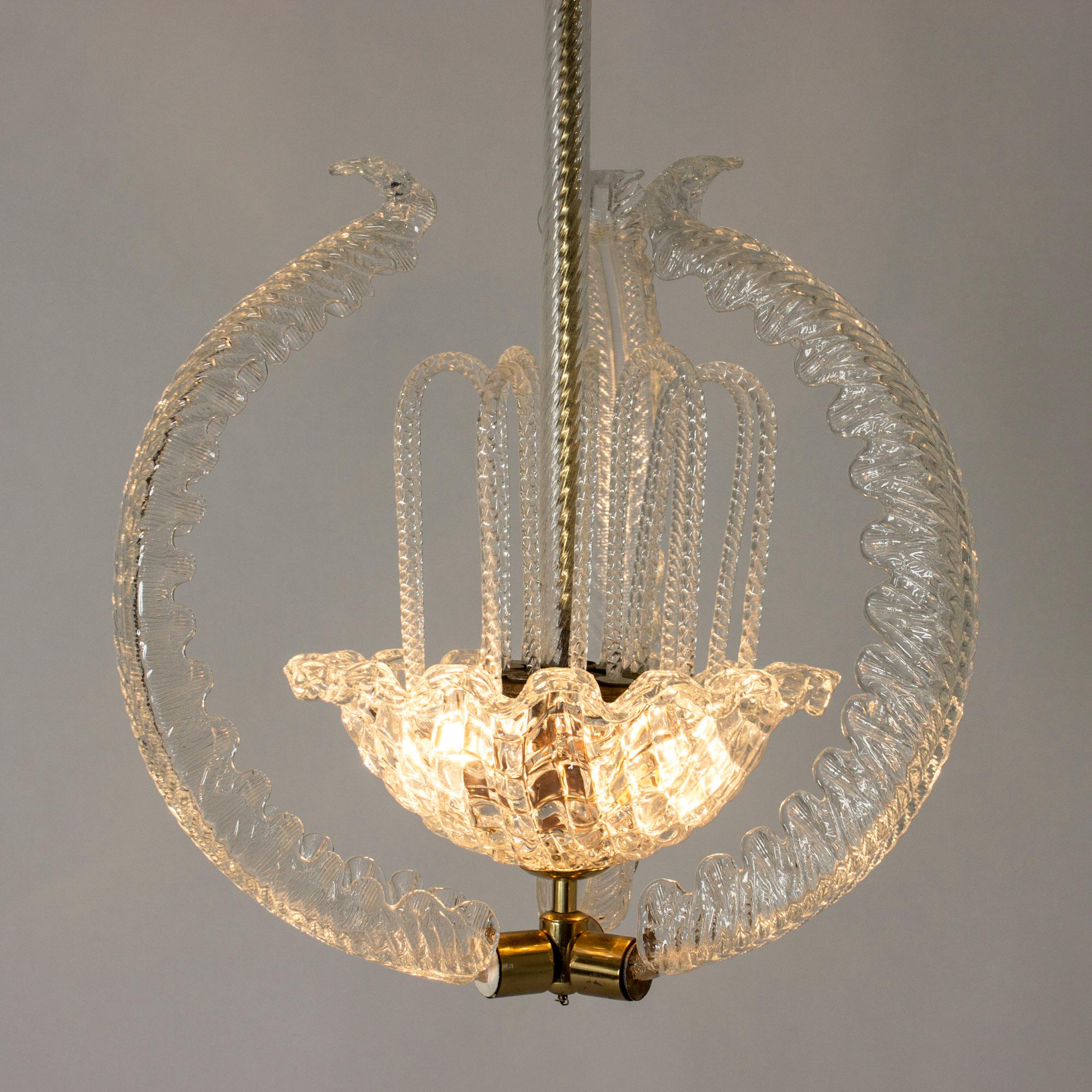 Exquisite handblown glass and brass chandelier by Fritz Kurz for Orrefors. Three glass feathers embrace a bowl in the middle with cascading glass inside. The brass pole and cup are encased in glass, the full effect of this chandelier is of a real