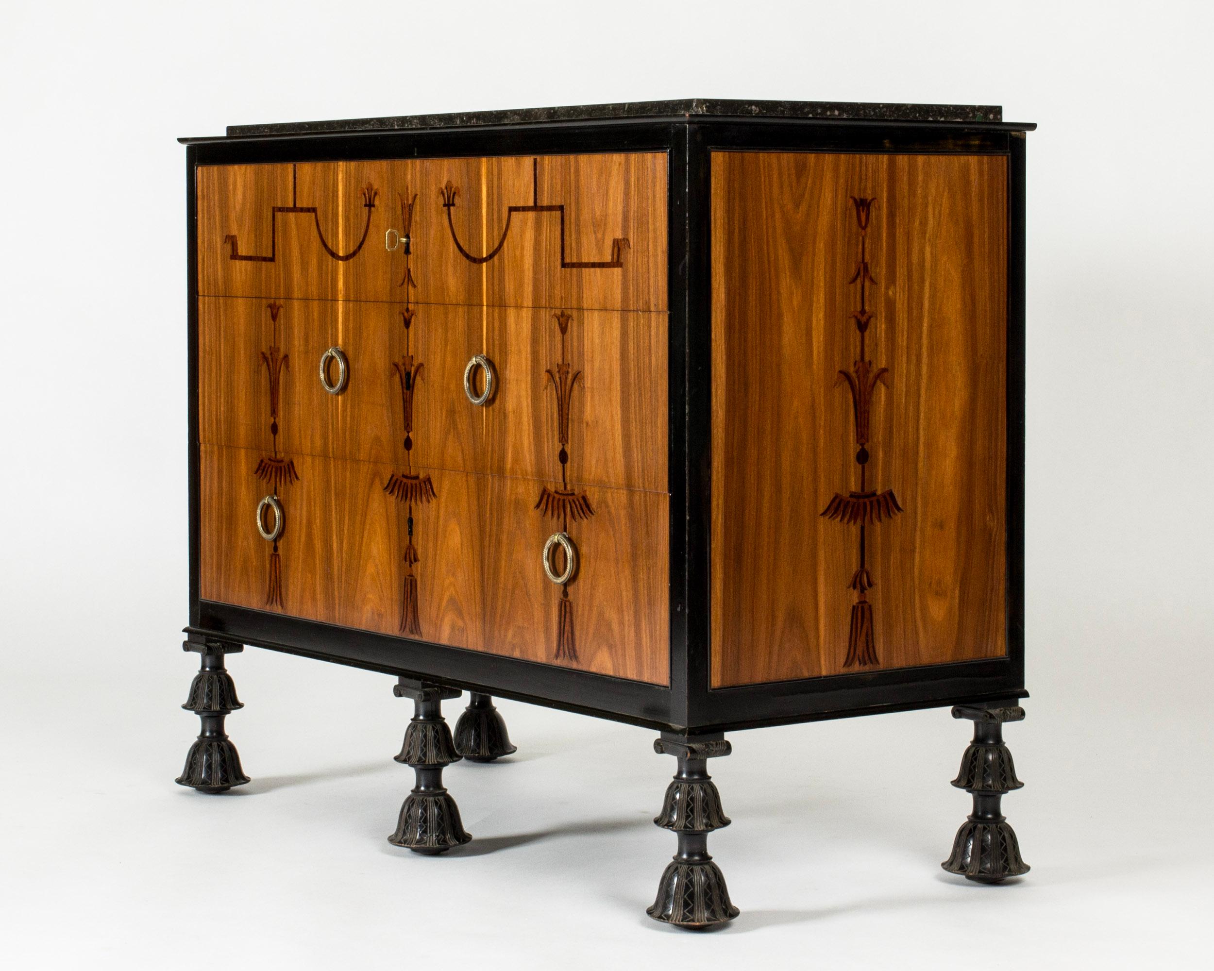 Superbe commode de la période suédoise Grace par Axel Einar Hjorth. Belles façades en acajou et plateau en marbre noir. Incrustations avec un design classique, pieds sculptés de manière élaborée.

Dans les années 1920, avant de commencer à