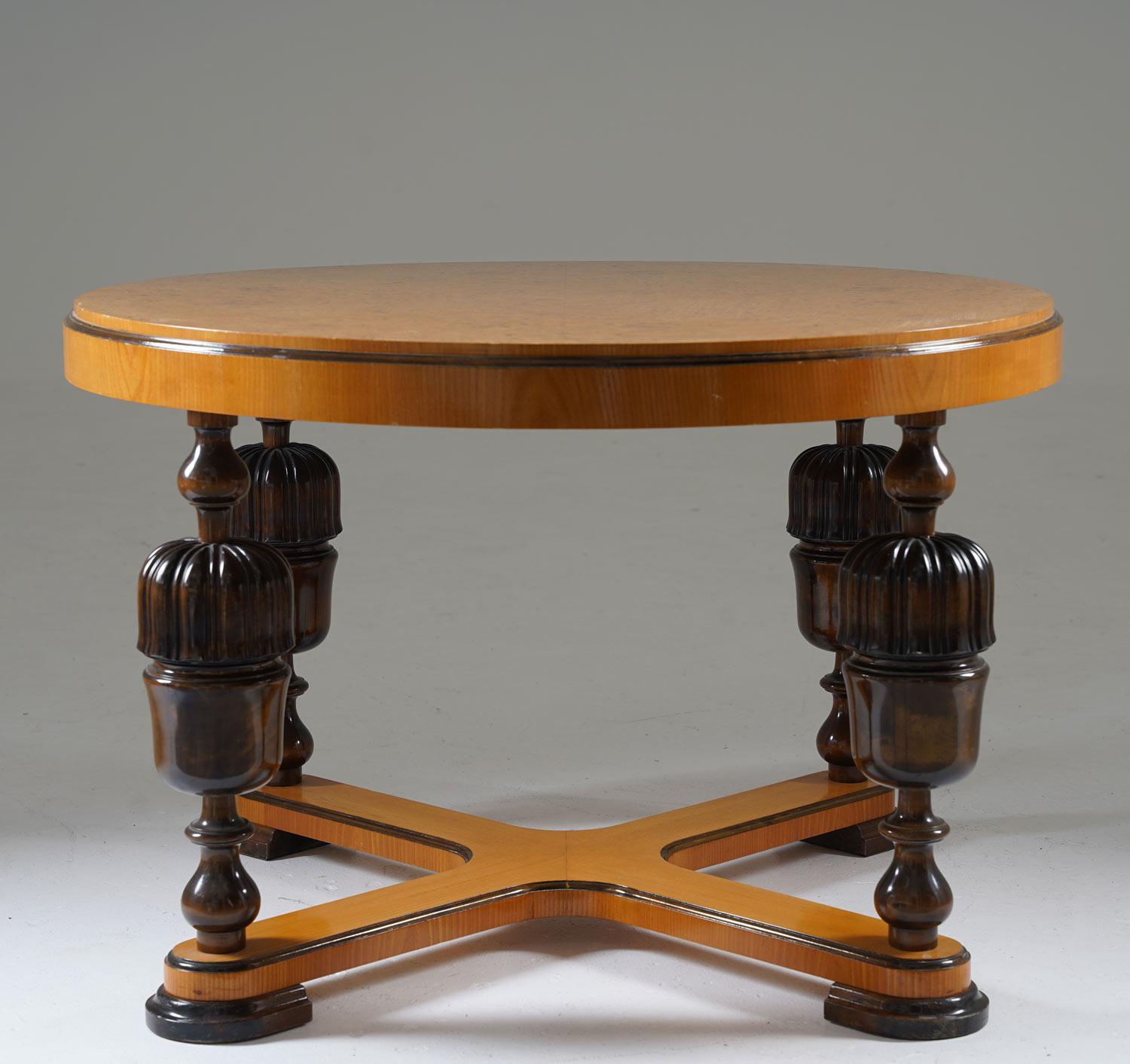 Elegant Swedish grace / Art Deco coffee table, produced in Sweden, 1930s.
This table features a thick circular table top in elm root veneer. The table top is supported by four richly decorated legs, connected by a cross at the bottom.

Condition: