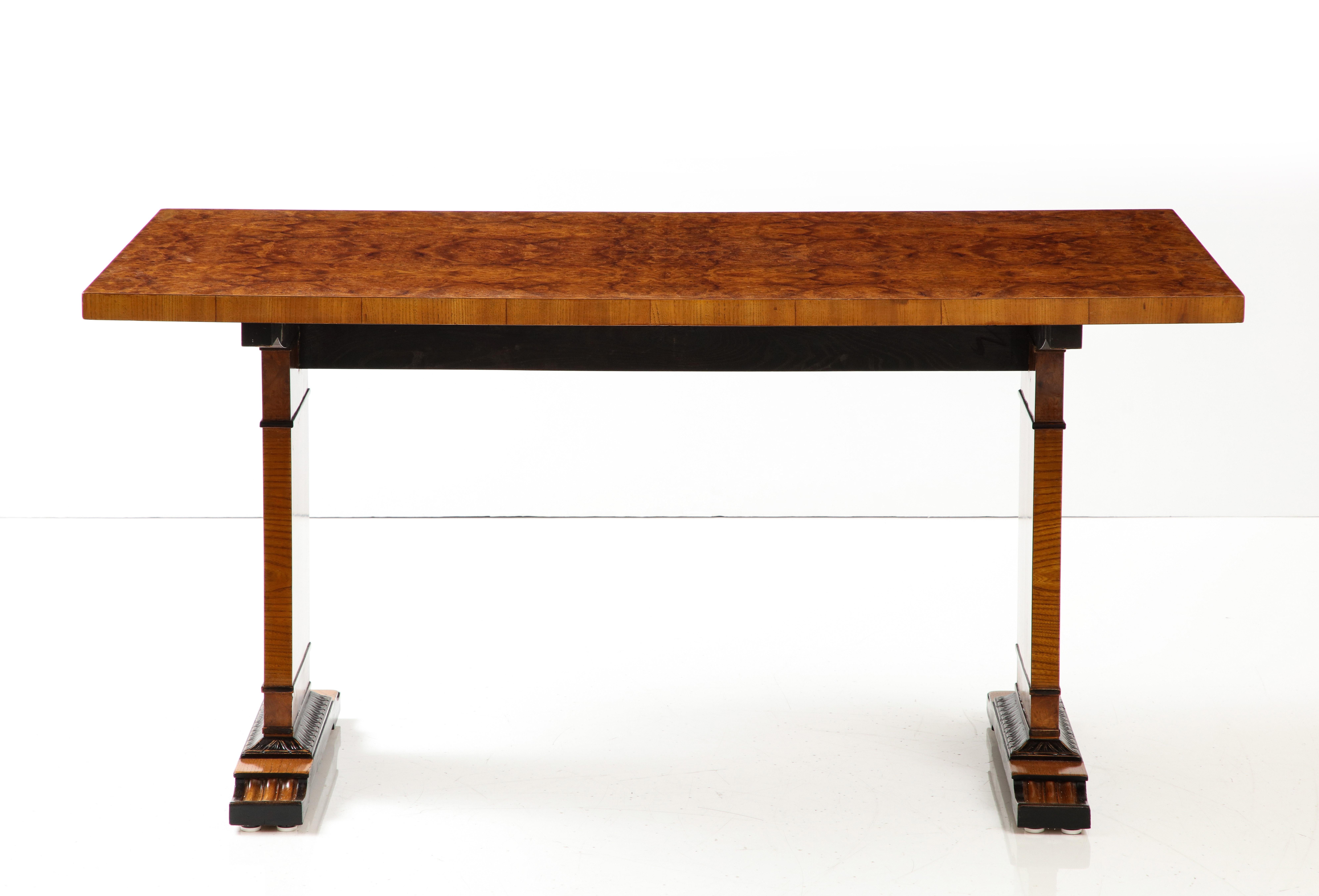 A Swedish Grace, elm, elm root and ebonized table or desk by Erik Chambert, with a rectangular top raised on rectangular supports with leaf-tip carving and carved scrolled feet.