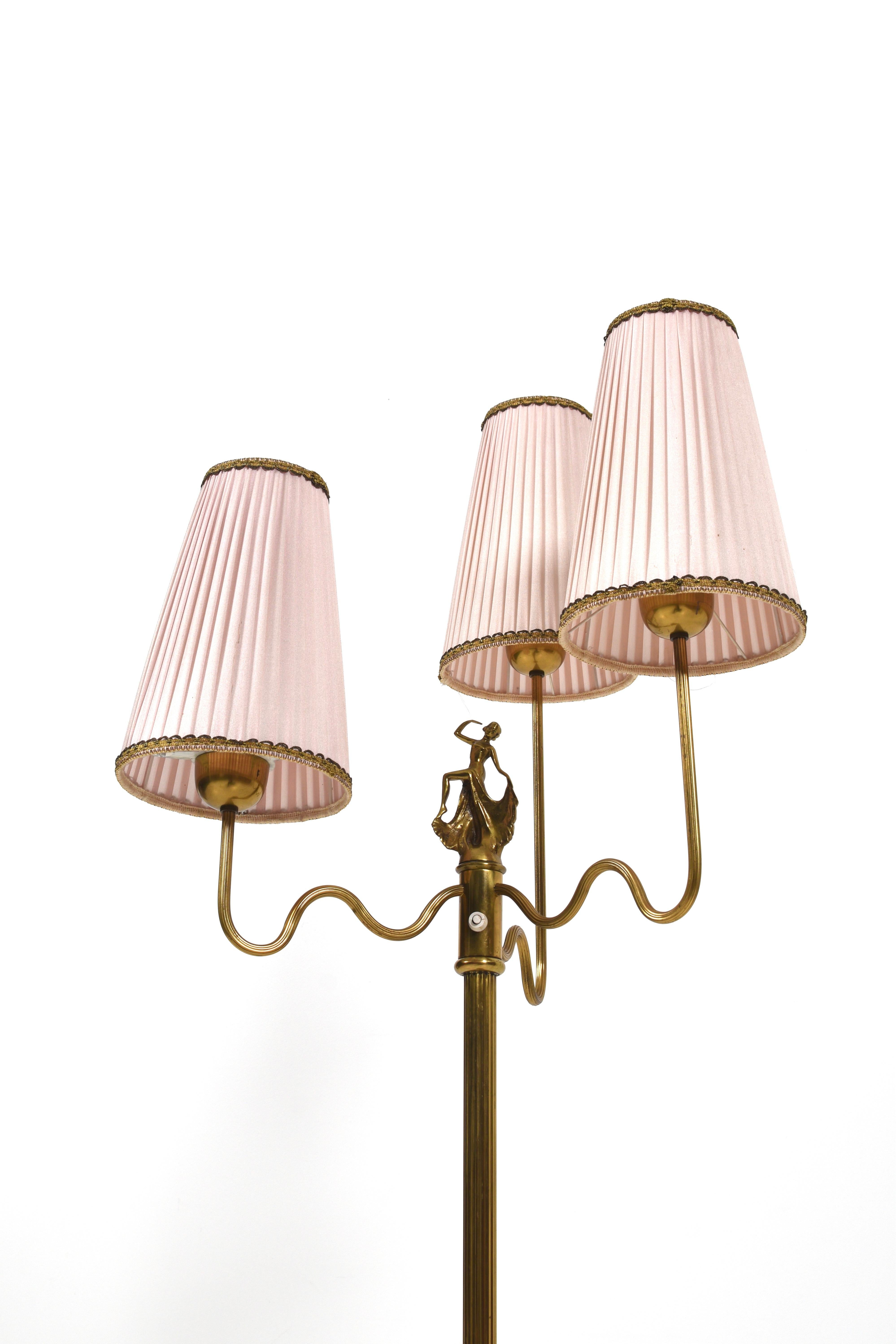 This elegantly designed floor lamp from the 1930s is a true work of art of its time. Crafted from polished brass, it adds a timeless elegance to whatever room it is placed in. 

With three curved arms, the lamp reaches upwards and holds beautiful