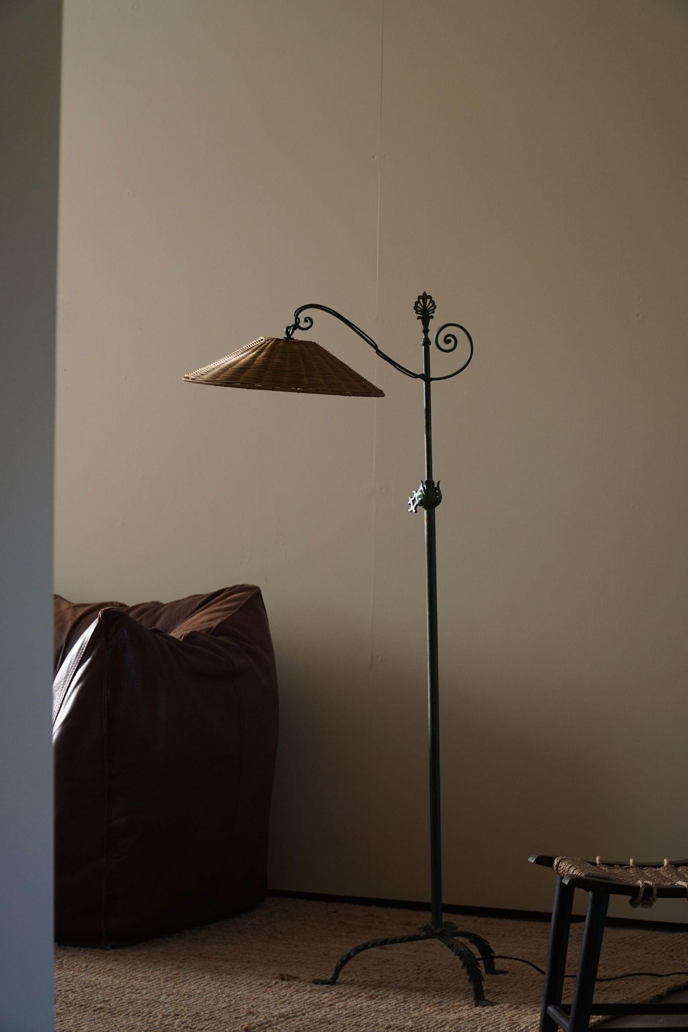 This rare beauty of a floor lamp, model 20210, sold by Nordiska Kompaniet in the 1930s, epitomizes the Swedish Grace style with its harmonious blend of classical motifs and refined details. Crafted from green-painted wrought iron, it features