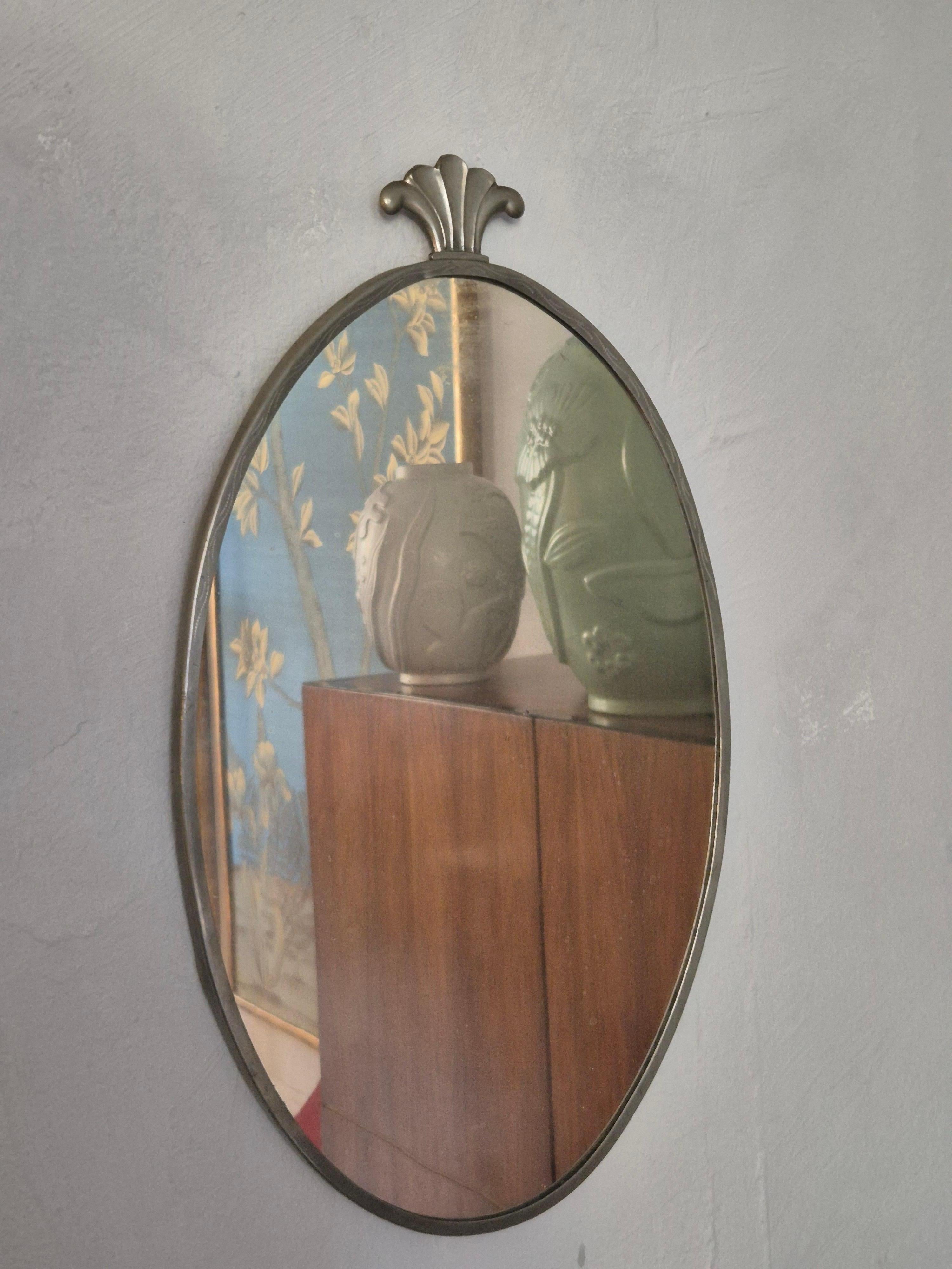 Ein Spiegel aus Zinn, oben mit einem eleganten Dekorelement. Schwedische Anmut / Art Deco 1920/30er Jahre. 

Spiegelglas hat Flecken und wird mit dem Alter gesprenkelt. Schöne Patina. Rahmen mit kleineren Unregelmäßigkeiten.