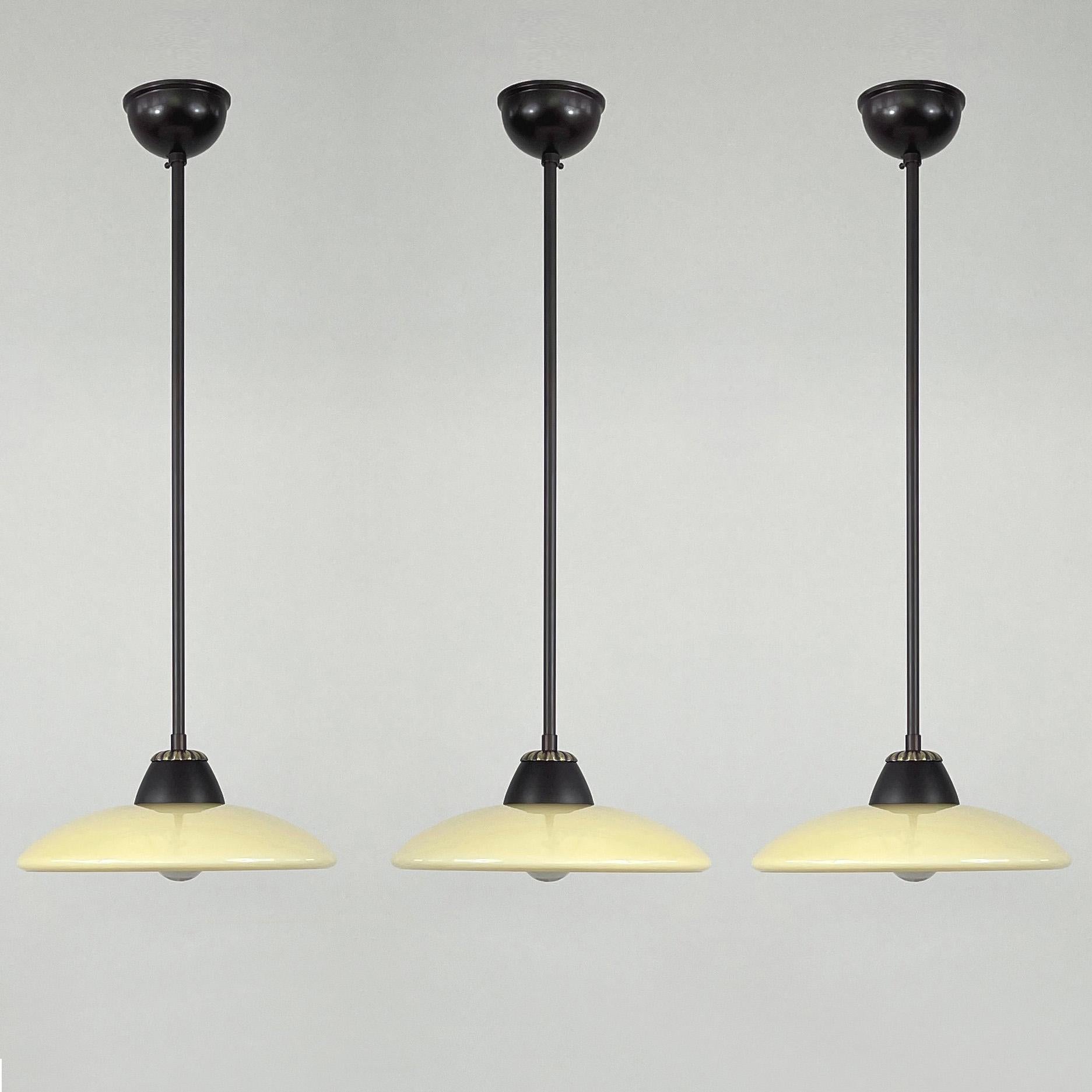 Questo fantastico set di 3 ciondoli è stato progettato e prodotto in Svezia negli anni '40 durante il periodo Swedish Grace (Art Deco svedese).

Le luci sono dotate di paralumi opalini a cupola color crema scuro con finitura liscia e lucida e