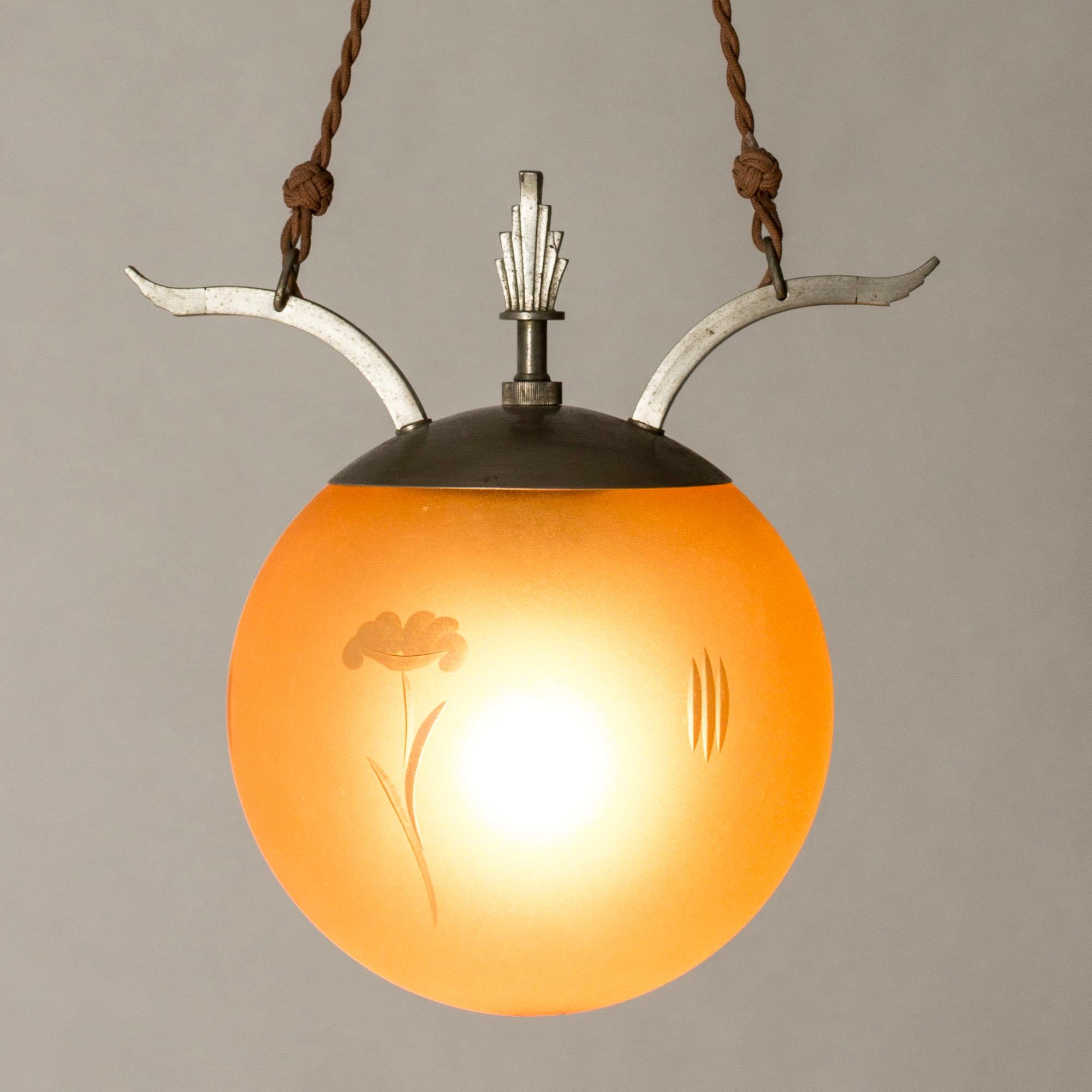 Elegant Swedish Grace ceiling light, with a pewter and pale orange colored glass shade with a cut decor. Graphic, functionalist design. Original textile chord suspension.