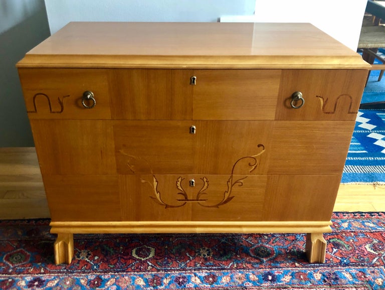 Sweet three-drawer Swedish Art Deco chest with intarsia mixed wood inlay on patchwork oak and birch veneer, brass fittings.