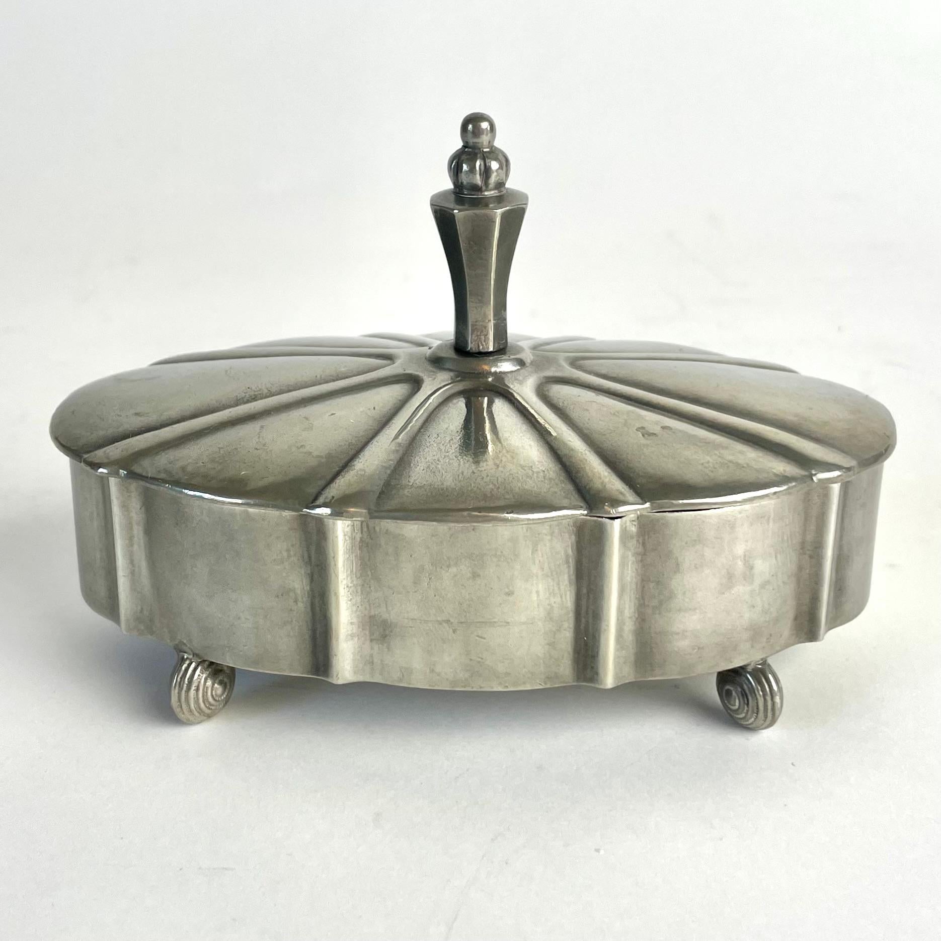
Scatola con coperchio in peltro Swedish Grace di Edvin Ollers, 1924

Una rara e squisita scatola con coperchio in peltro disegnata dal famoso artista e designer svedese Edvin Ollers (1888-1959). Datato 1924 (anno svedese X7), questo pezzo è un